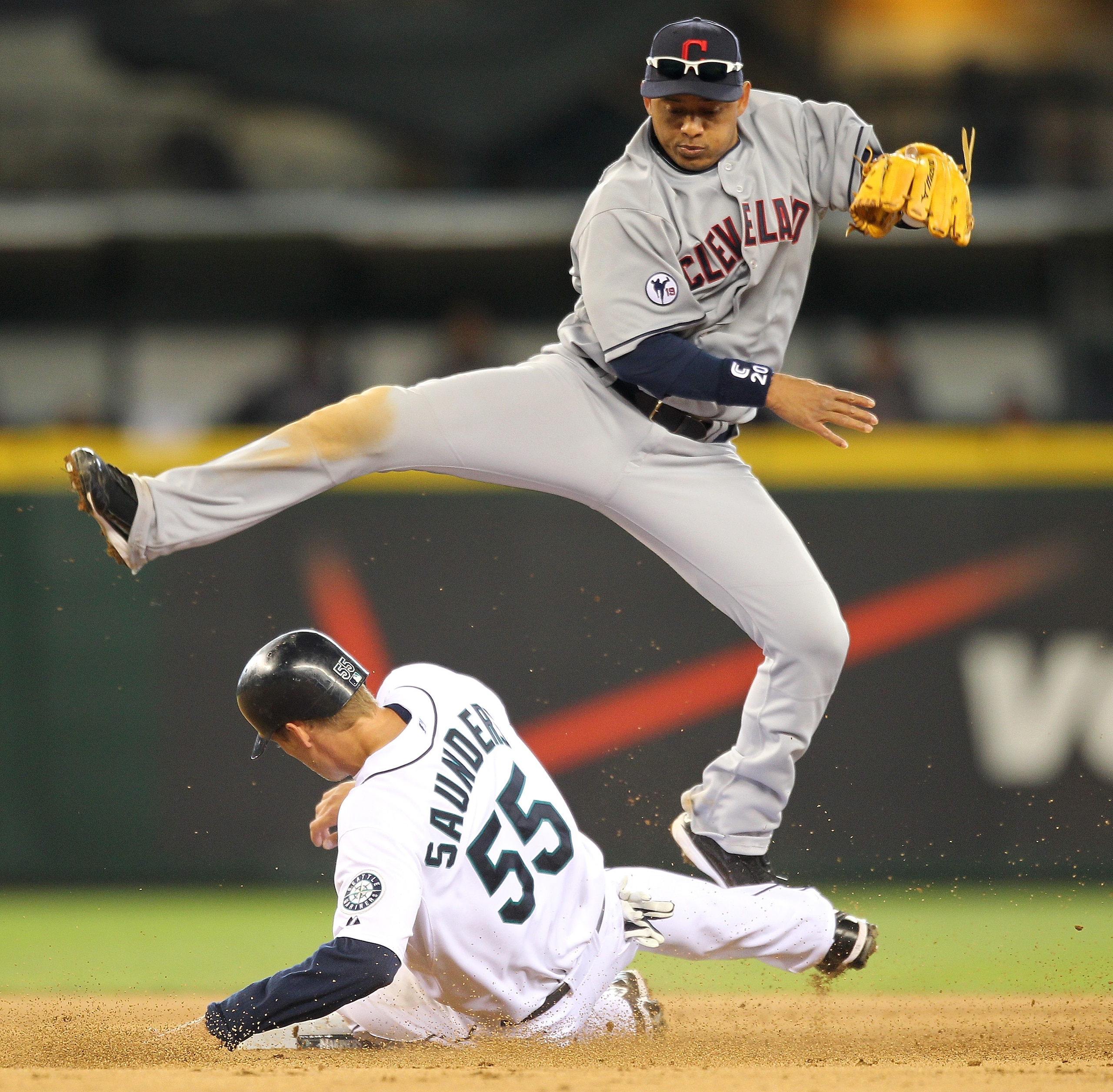 SEATTLE - APRIL 10:  Second baseman Orlando Cabrera #20 of the Cleveland Indians hops over Michael Saunders #55 of the Seattle Mariners on a double play in the fifth inning at Safeco Field on April 10, 2011 in Seattle, Washington. (Photo by Otto Greule Jr
