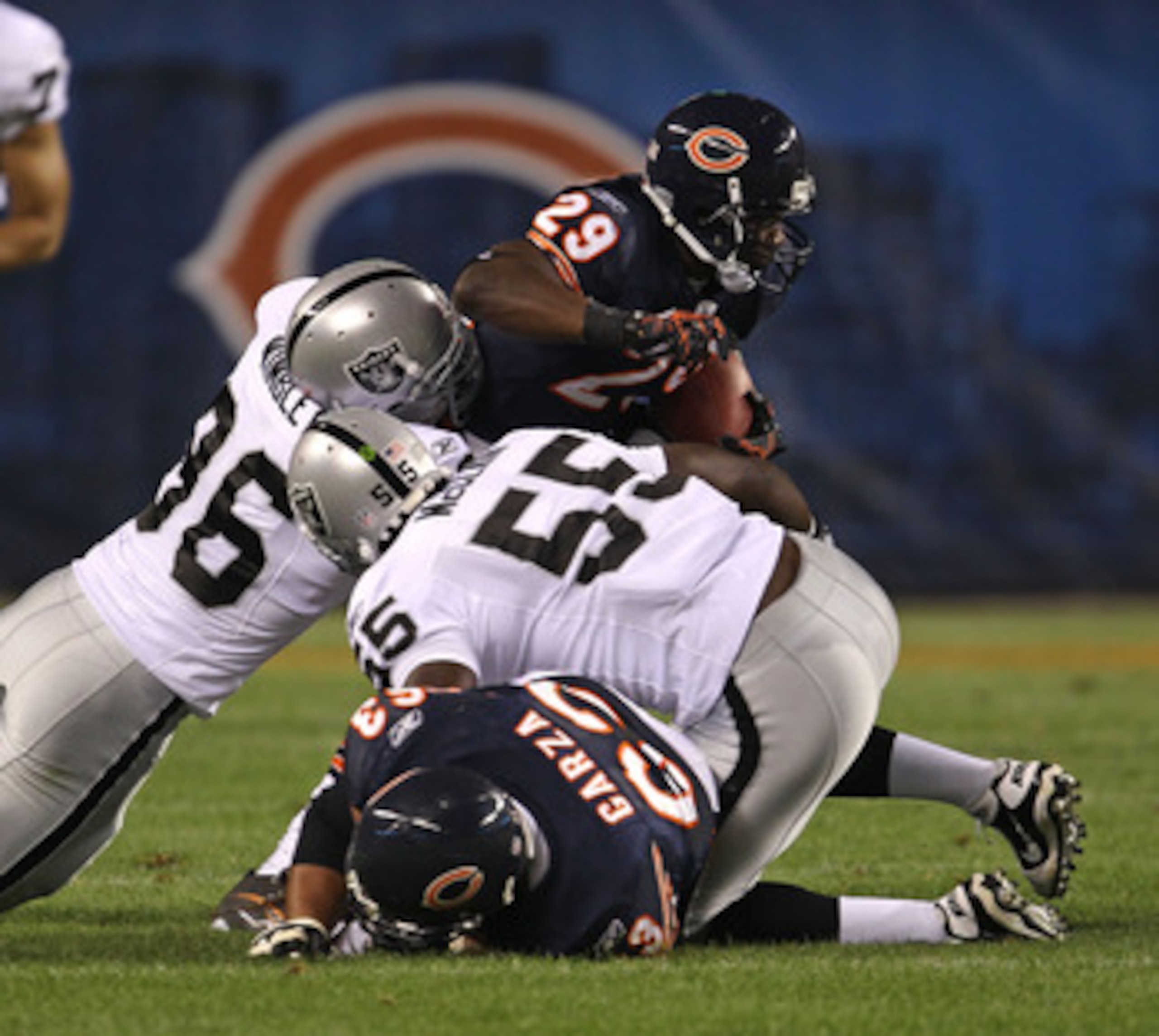 CHICAGO - AUGUST 21: Chester Taylor #29 of the Chicago Bears tries to break away from Kamerion Wimbley #96 and Rolando McClain #55 of the Oakland Raiders and past teammate Roberto Garza #63 during a preseason game at Soldier Field on August 21, 2010 in Ch