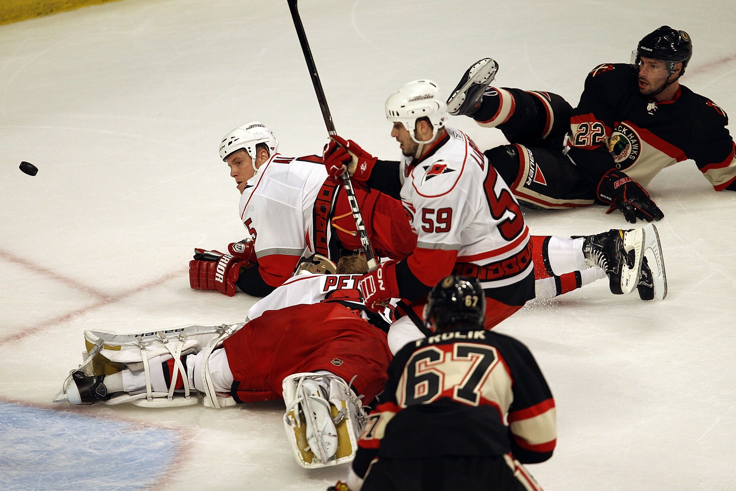 CHICAGO, IL - MARCH 04: Bryan Allen #5 and Chad LaRose #59 of the Carolina Hurricanes and Michael Frolik #67 and Troy Brouwer #22 of the Chicago Blackhawks watch the puck after Allen collided with goalie Justin Peters #60 at the United Center on March 4,