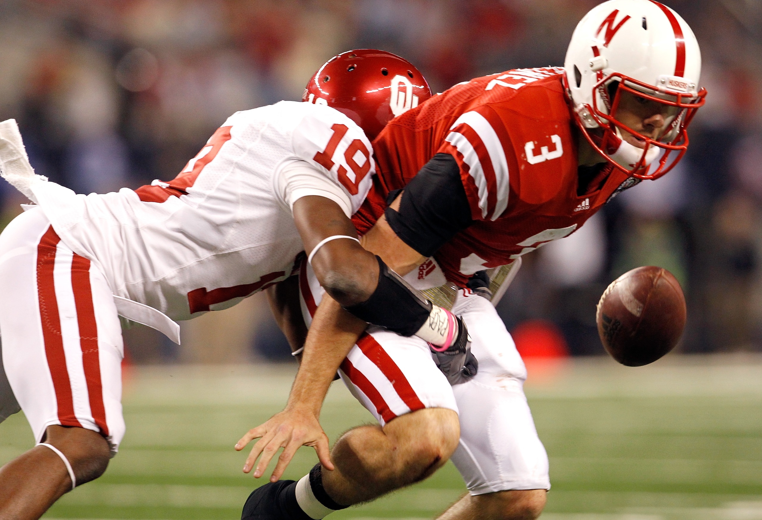 ARLINGTON, TX - DECEMBER 04: Quarterback Taylor Martinez #3 of the Nebraska Cornhuskers fumbles the ball under pressure from defensive back Demontre Hurst #19 of the Oklahoma Sooners at Cowboys Stadium on December 4, 2010 in Arlington, Texas. The Sooners ARLINGTON, TX - DECEMBER 04: Quarterback Taylor Martinez #3 of the Nebraska Cornhuskers fumbles the ball under pressure from defensive back Demontre Hurst #19 of the Oklahoma Sooners at Cowboys Stadium on December 4, 2010 in Arlington, Texas. The Sooners