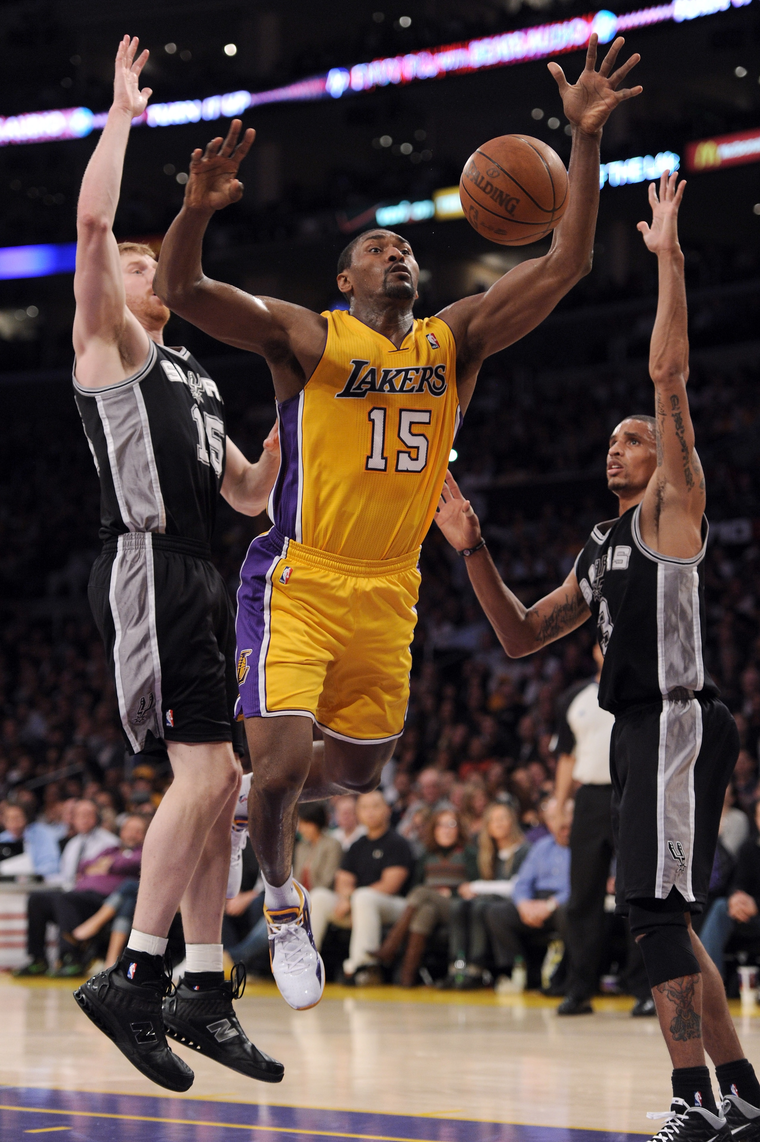 LOS ANGELES, CA - APRIL 12:  Ron Artest #15 of the Los Angeles Lakers is fouled as he attempts a shot in front of Matt Bonner #15 and George Hill #3 of the San Antonio Spurs at Staples Center on April 12, 2011 in Los Angeles, California.  NOTE TO USER: Us
