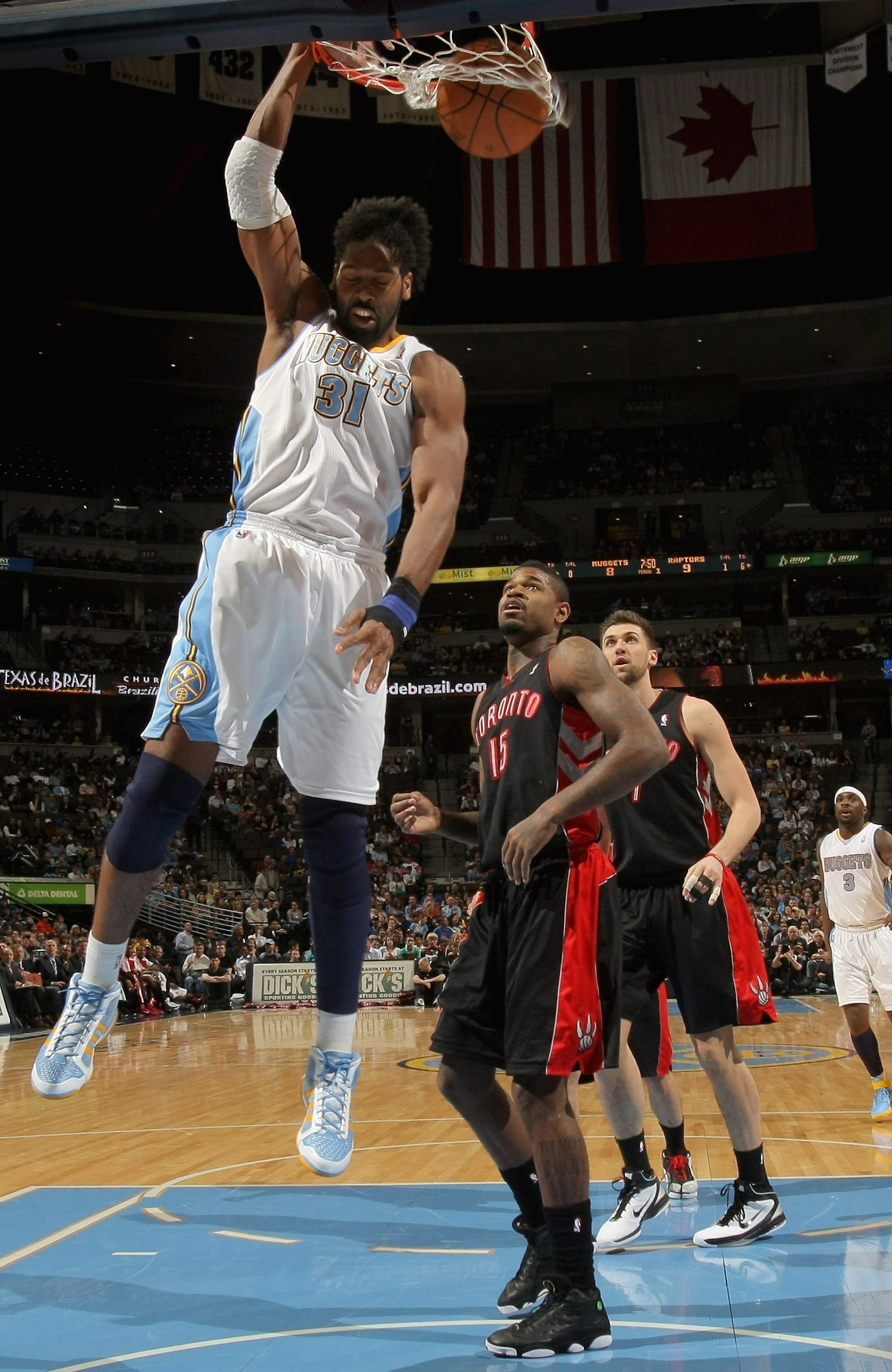 DENVER, CO - MARCH 21:  Nene #31 of the Denver Nuggets dunks the ball in front of Amir Johnson #15 of the Toronto Raptors at the Pepsi Center on March 21, 2011 in Denver, Colorado. NOTE TO USER: User expressly acknowledges and agrees that, by downloading