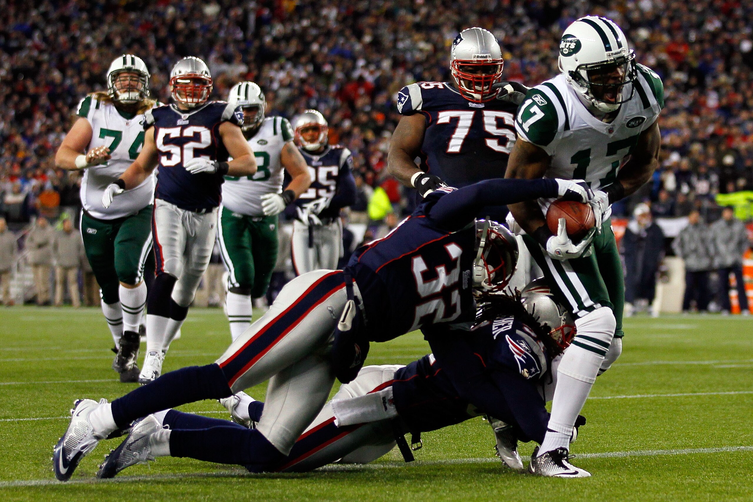 FOXBORO, MA - JANUARY 16:  Braylon Edwards #17 of the New York Jets scores a second quarter touchdown as Devin McCourty #32 and Brandon Meriweather #31 of the New England Patriots attempt to tackle during their 2011 AFC divisional playoff game at Gillette
