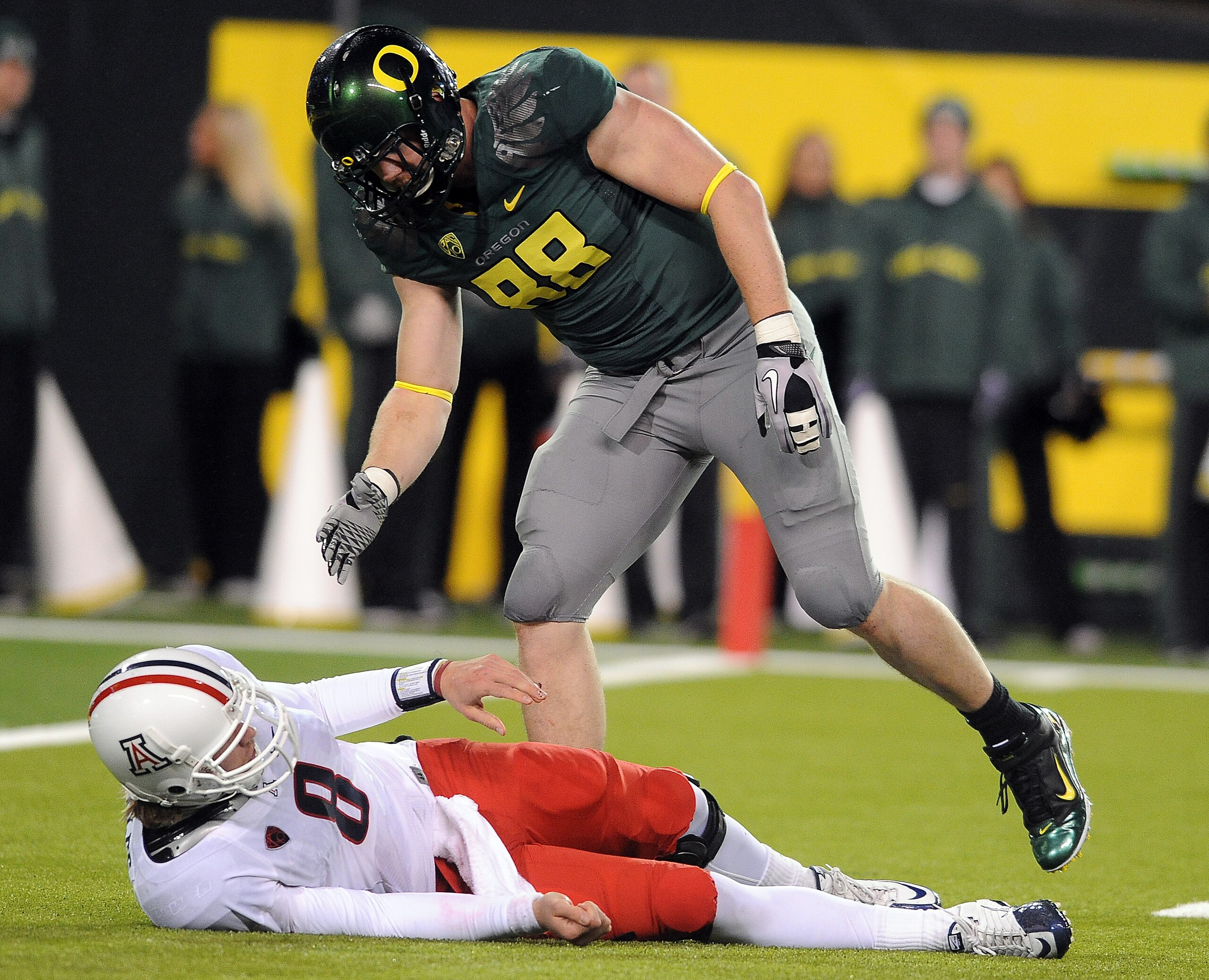 EUGENE, OR - NOVEMBER 26: Quarterback Nick Foles #8 of the Arizona Wildcats is helped up by defensive end Brandon Bair #88 of the Oregon Ducks in the fourth quarter of the game at Autzen Stadium on November 26, 2010 in Eugene, Oregon. The Ducks won the ga