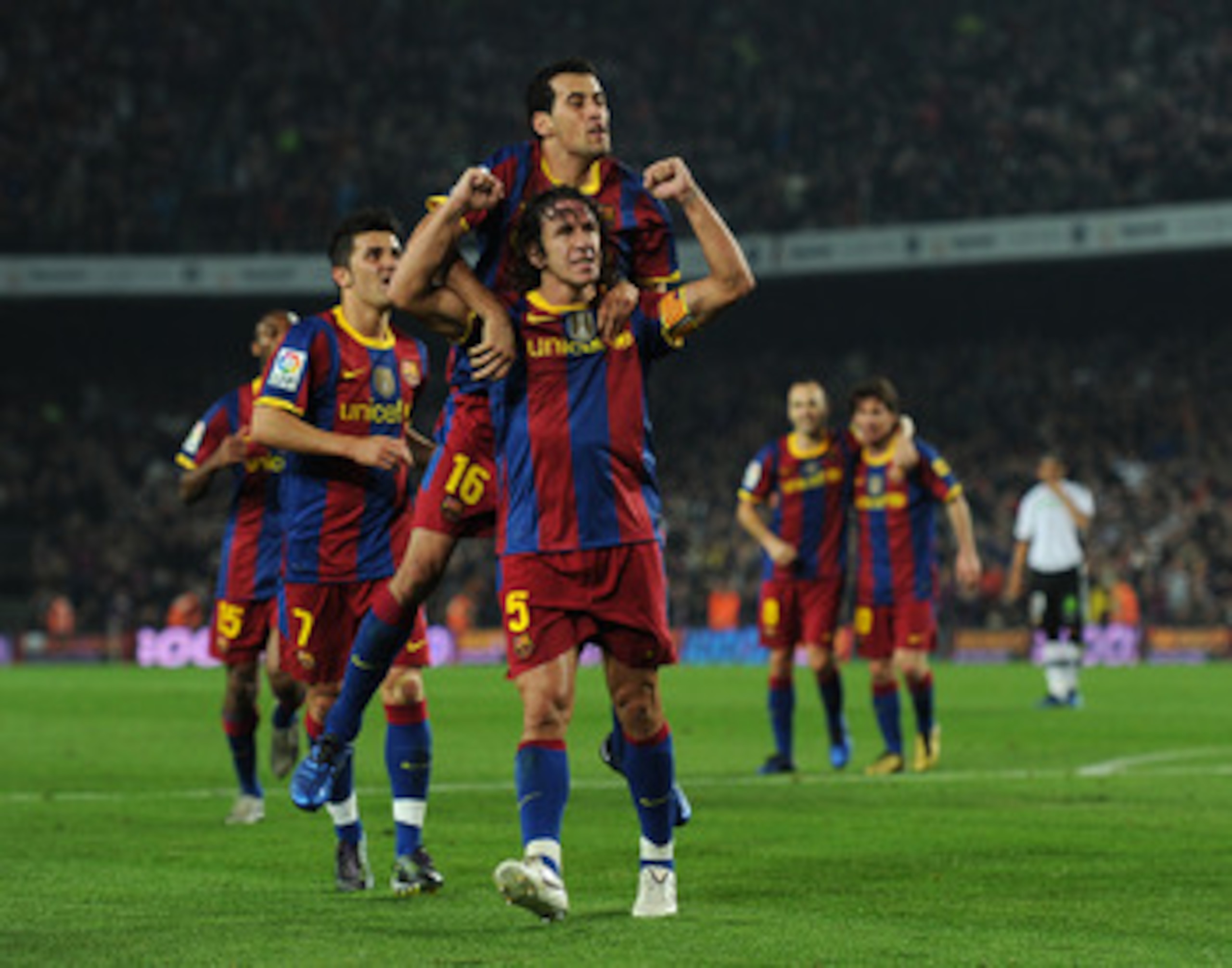 BARCELONA, SPAIN - OCTOBER 16:  Carles Puyol (C) of Barcelona celebrates scoring his sides second goal with his teammate Sergio Busquets (Top) during the La Liga match between Barcelona and Valencia at the Camp Nou stadium on October 16, 2010 in Barcelona