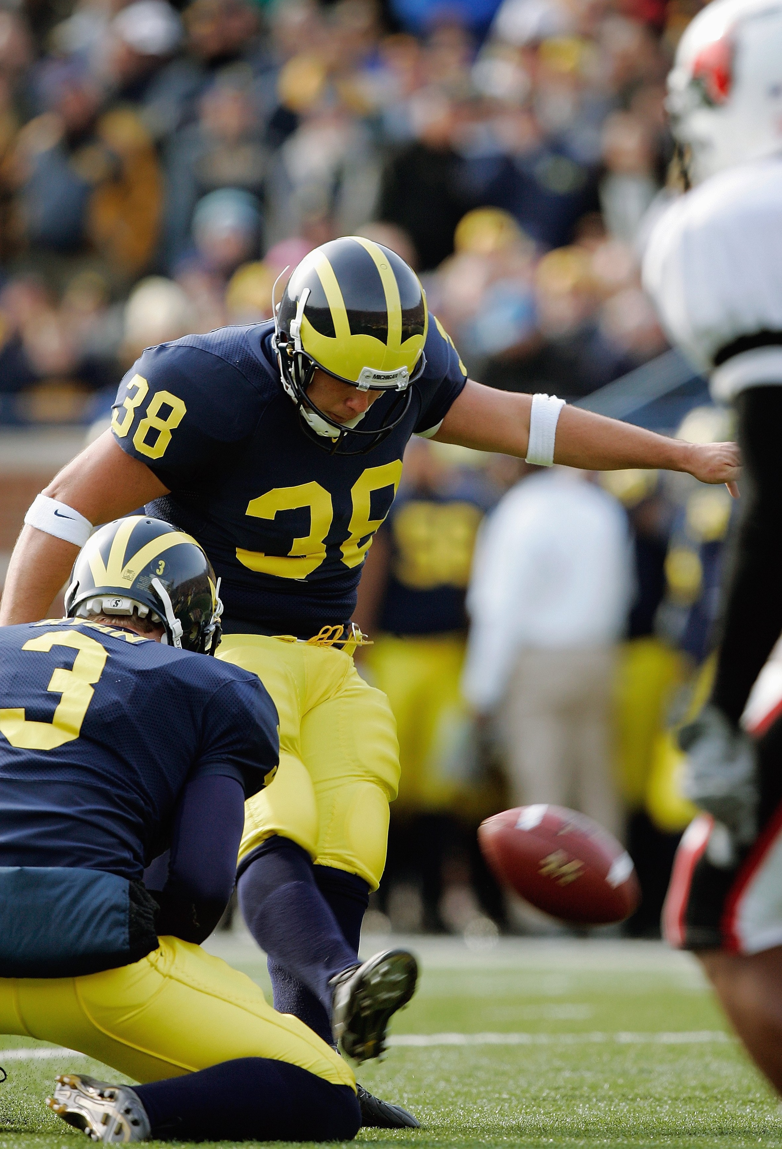 ANN ARBOR, MI - NOVEMBER 4:  Garrett Rivas #38 of the Michigan Wolverines kicks from holder Ross Ryan #3 during the NCAA game against the Ball State Cardinals on November 4, 2006 at Michigan Stadium in Ann Arbor, Michigan. Michigan won 34-26. (Photo by Br