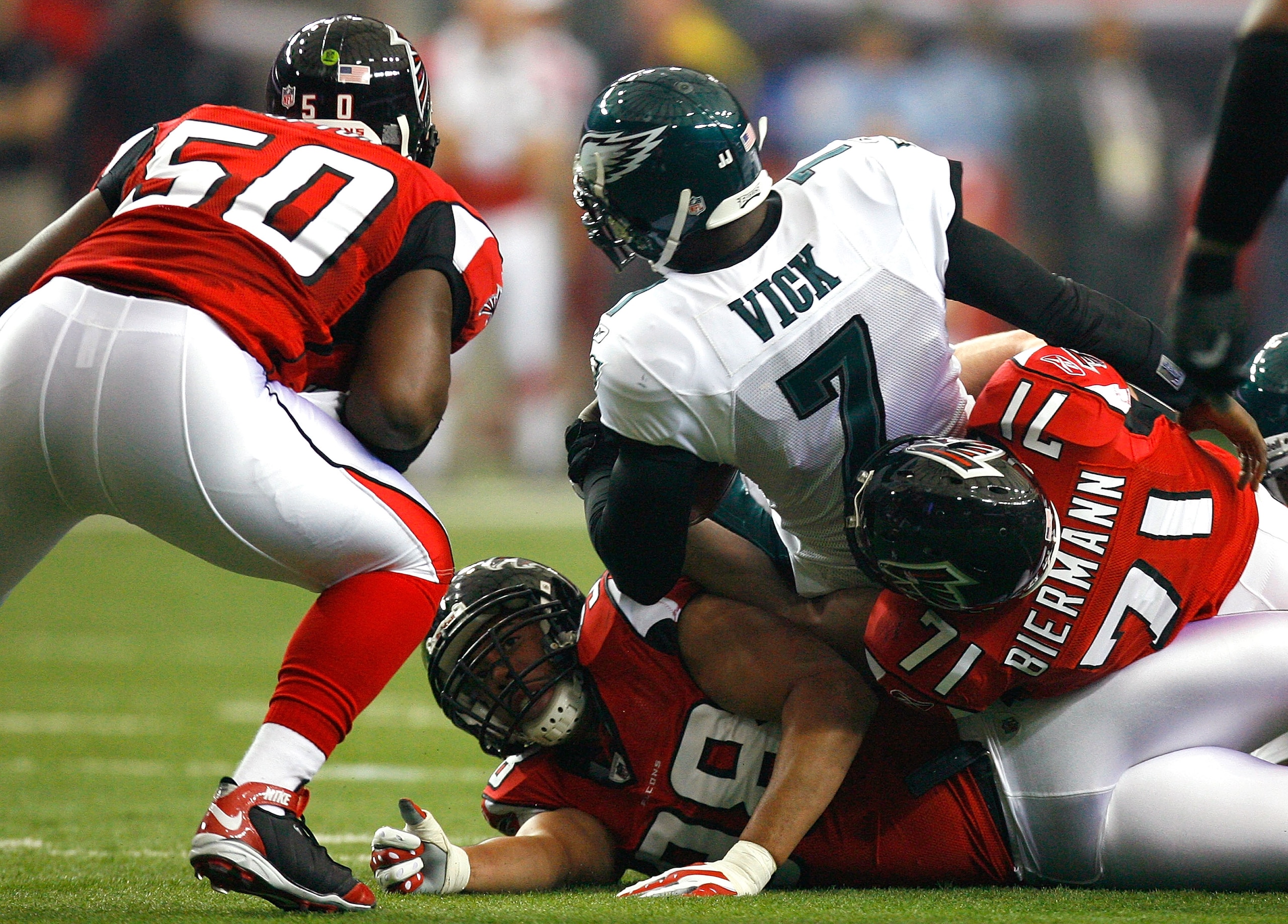 ATLANTA - DECEMBER 06:  Michael Vick #7 of the Philadelphia Eagles is tackled by Kroy Biermann #71, Curtis Lofton #50 and Jamaal Anderson #98 of the Atlanta Falcons at Georgia Dome on December 6, 2009 in Atlanta, Georgia.  (Photo by Kevin C. Cox/Getty Ima