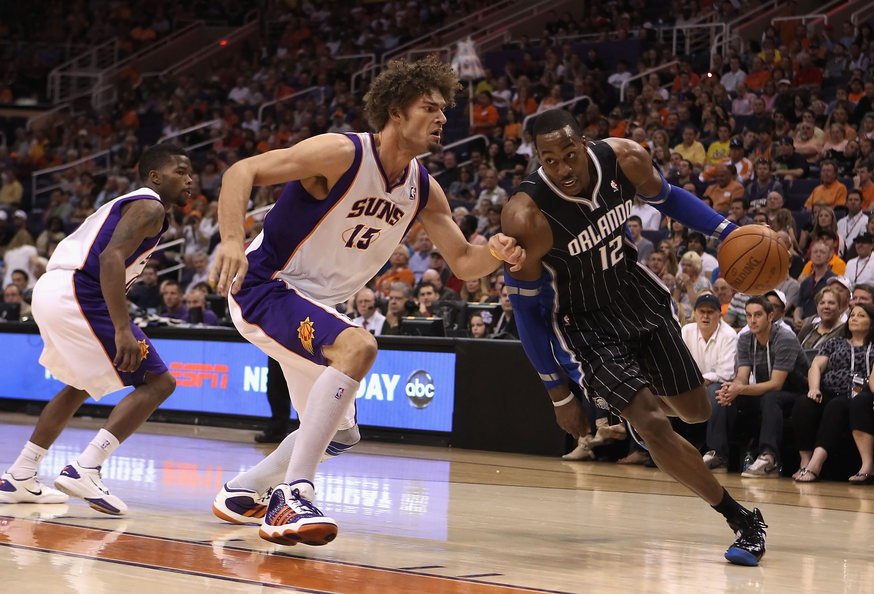 PHOENIX, AZ - MARCH 13:  Dwight Howard #12 of the Orlando Magic drives the ball past Robin Lopez #15 of the Phoenix Suns during the NBA game at US Airways Center on March 13, 2011 in Phoenix, Arizona.  NOTE TO USER: User expressly acknowledges and agrees