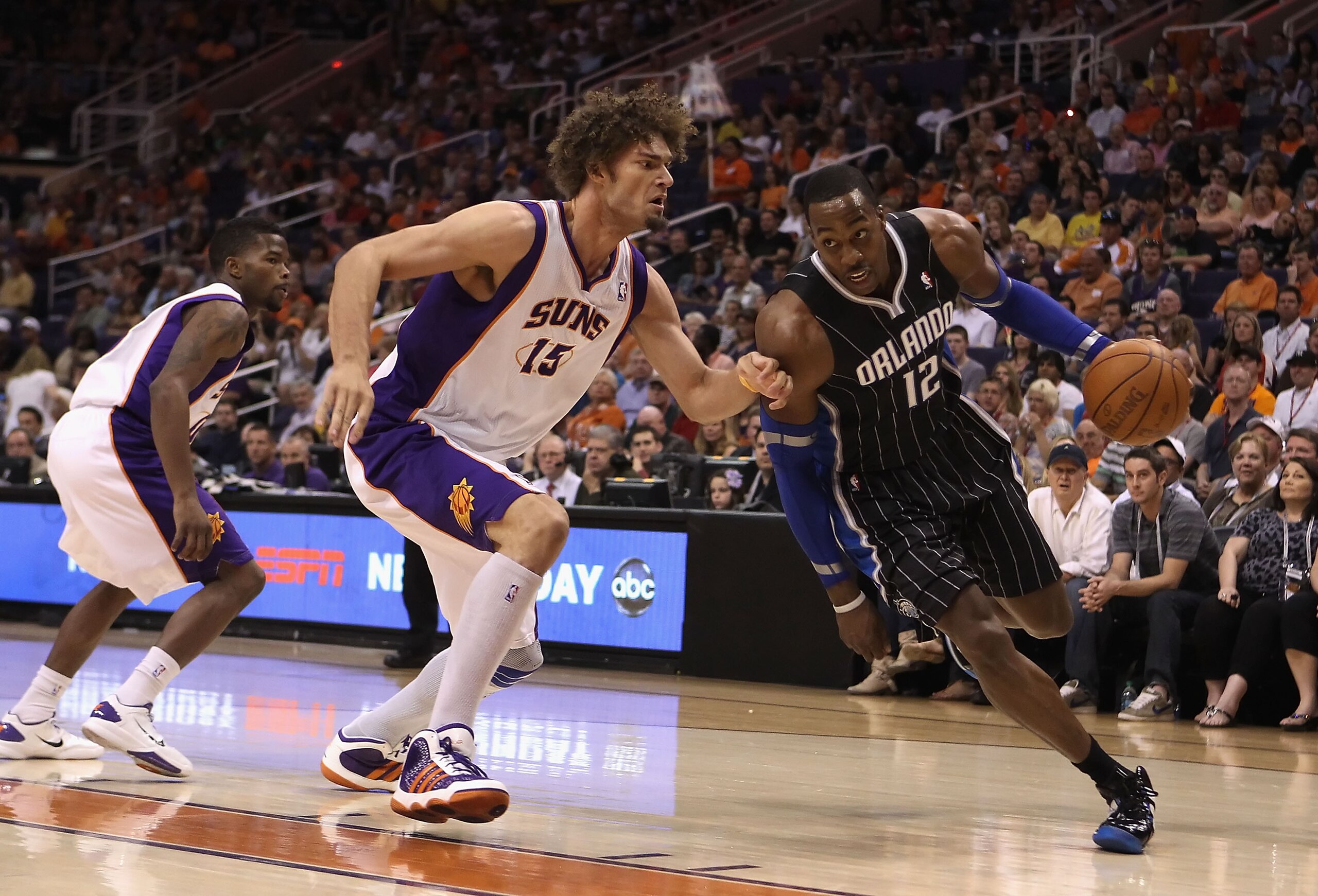 PHOENIX, AZ - MARCH 13:  Dwight Howard #12 of the Orlando Magic drives the ball past Robin Lopez #15 of the Phoenix Suns during the NBA game at US Airways Center on March 13, 2011 in Phoenix, Arizona.  NOTE TO USER: User expressly acknowledges and agrees