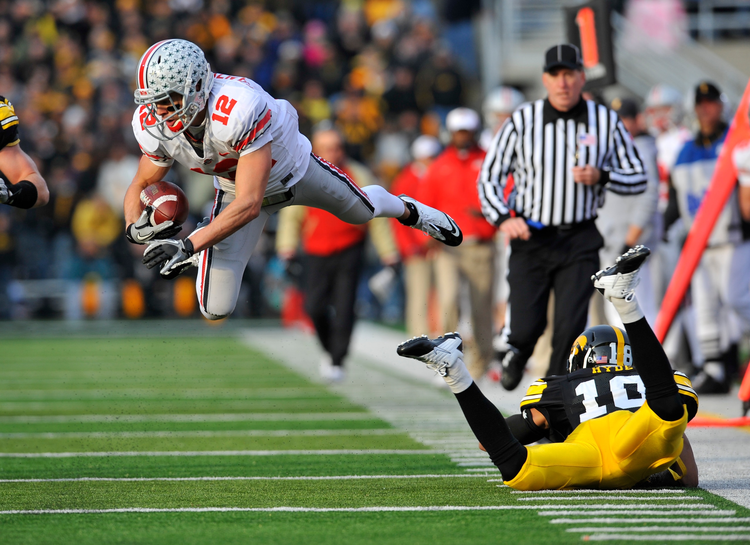 IOWA CITY, IA - NOVEMBER 20:  Defenisve back Micah Hyde #18 of the University of Iowa Hawkeyes trips up wide receiver Dane Sanzenbacher #12 of the Ohio State Buckeyes as he drove the ball down field during the first half of play at Kinnick Stadium on Nove