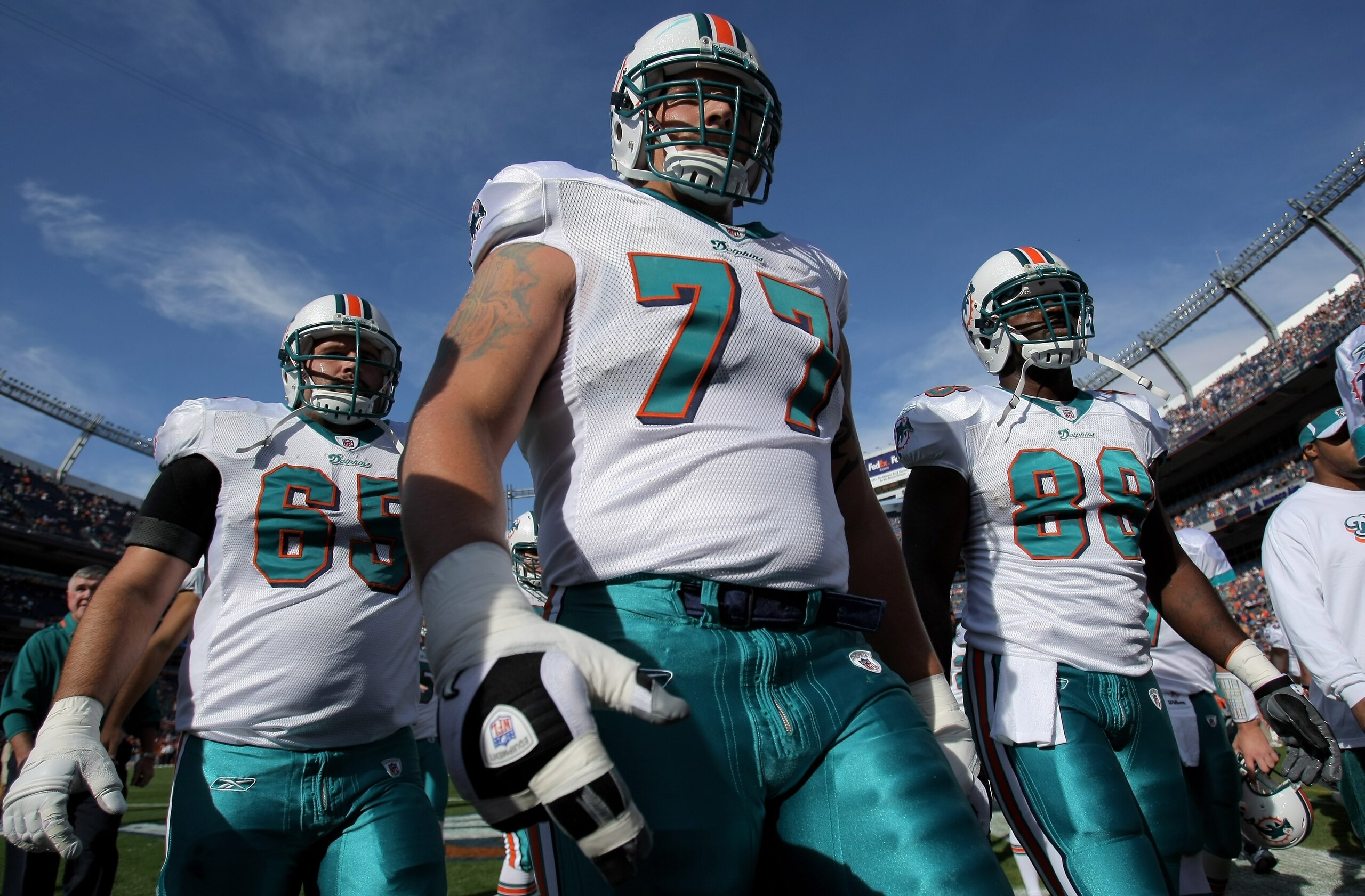 DENVER - NOVEMBER 02:  Guard Justin Smiley #65, tackle Jake Long #77 and tight end David Martin #88 of the Miami Dolphins leave the field after warming up prior to facing the Denver Broncos during NFL action at Invesco Field at Mile High on November 2, 20