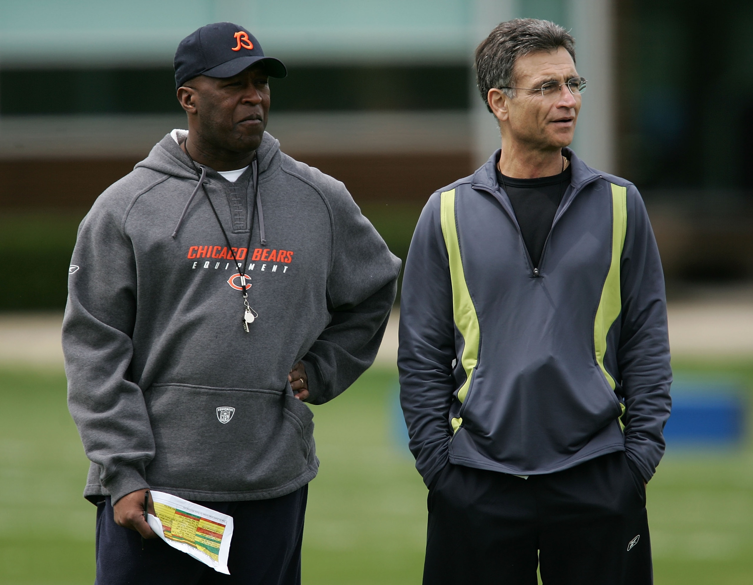 LAKE FOREST, IL - MAY 4:  The head coach Lovie Smith (L) and general manager Jerry Angelo of the Chicago Bears look over players during a rookie mini-camp practice at Halas Hall May 4, 2007 in Lake Forest, Illinois.  (Photo by Jonathan Daniel/Getty Images