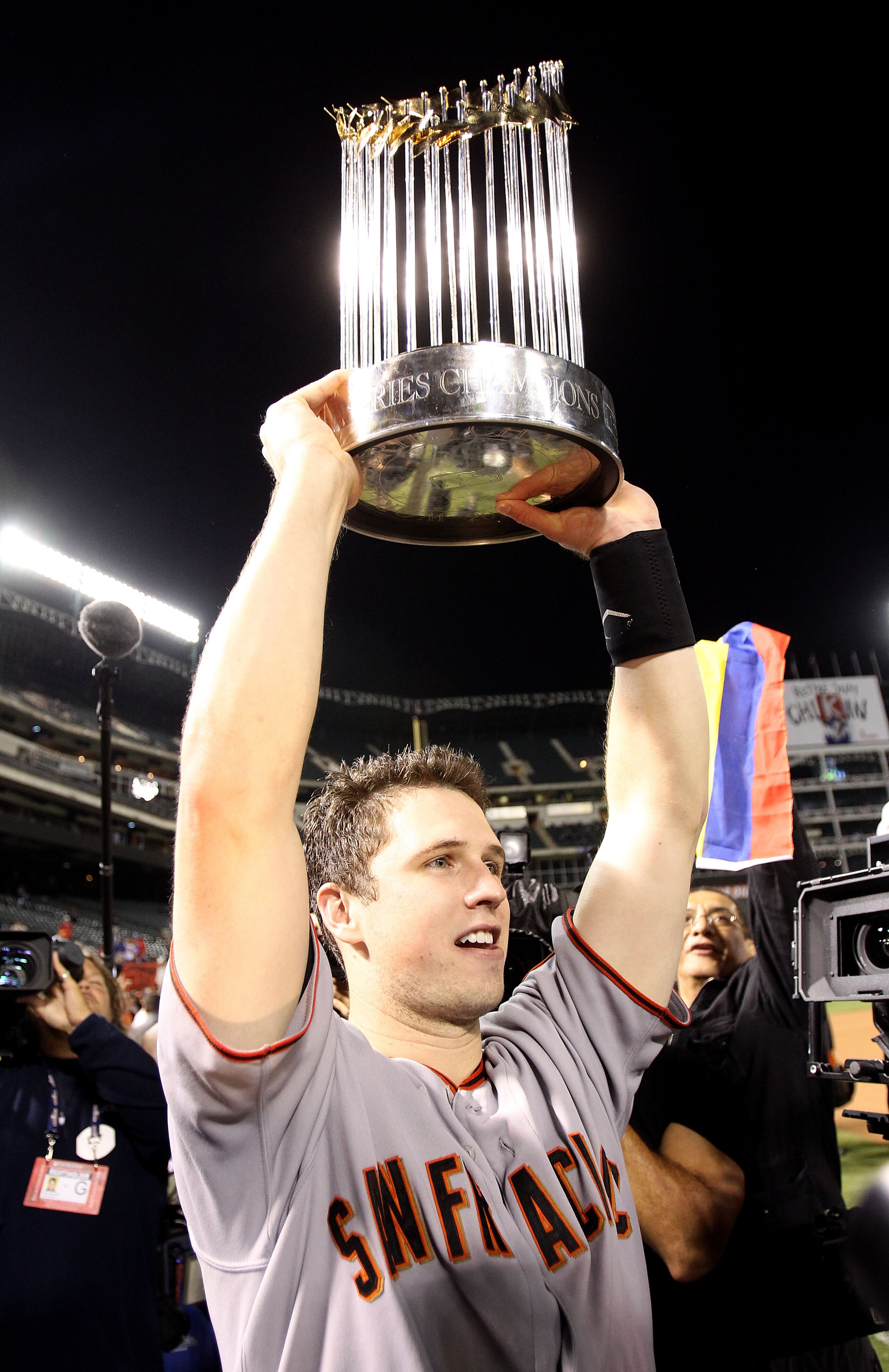 ARLINGTON, TX - NOVEMBER 01:  Buster Posey #28 of the San Francisco Giants celebrates with the World Series Championship trophy after the Giants won 3-1 the Texas Rangers in Game Five of the 2010 MLB World Series at Rangers Ballpark in Arlington on Novemb