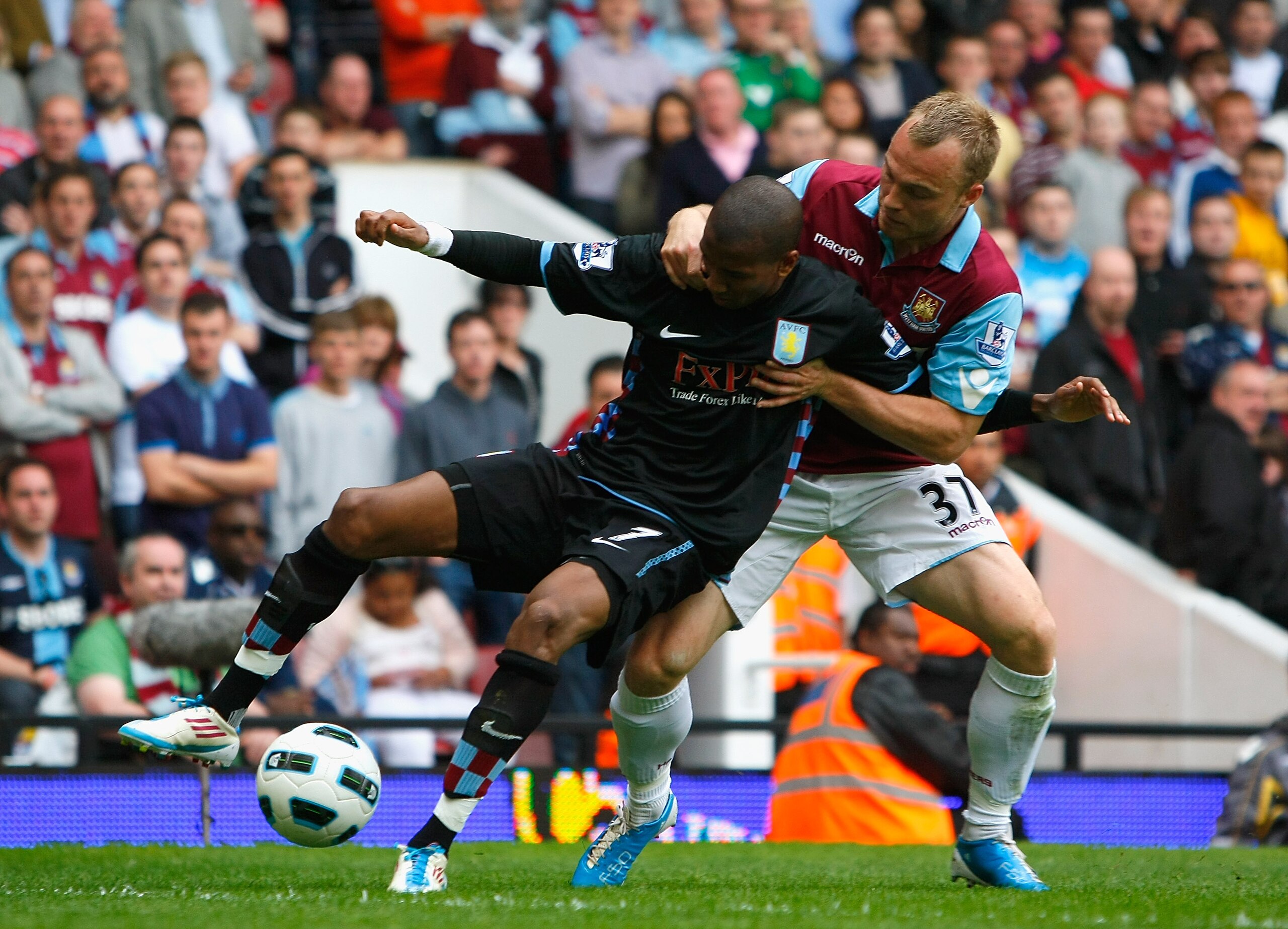 LONDON, ENGLAND - APRIL 16:  Ashley Young of Aston Villa holds off the challenge by Lars Jacobsen of West Ham United during the Barclays Premier League match between West Ham United and Aston Villa at the Boleyn Ground on April 16, 2011 in London, England