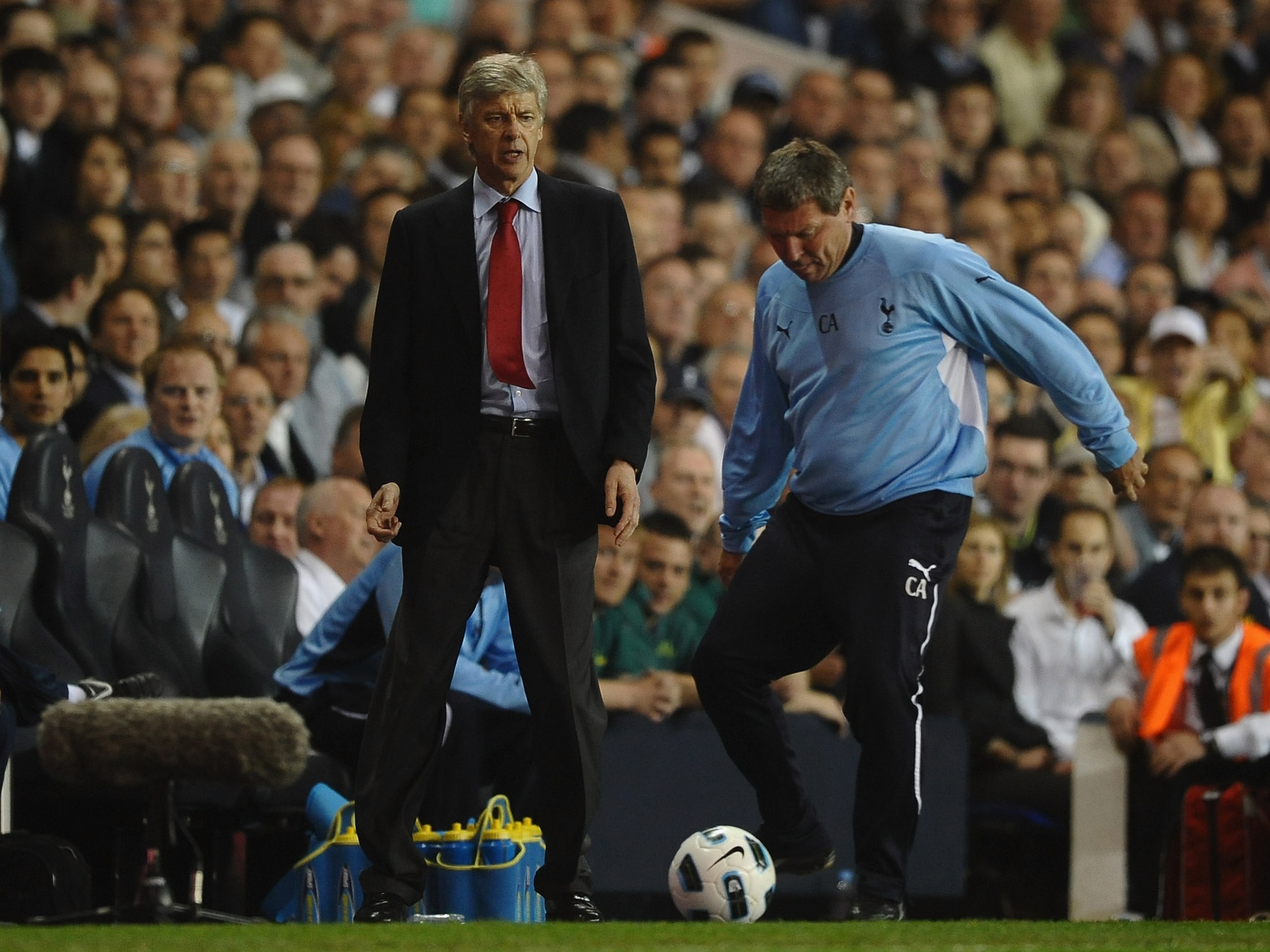 LONDON, ENGLAND - APRIL 20:  Spurs coach, Clive Allen kicks the match ball as Arsenal manager Arsene Wenger looks on during the Barclays Premier League match between Tottenham Hotspur and Arsenal at White Hart Lane on April 20, 2011 in London, England.  (