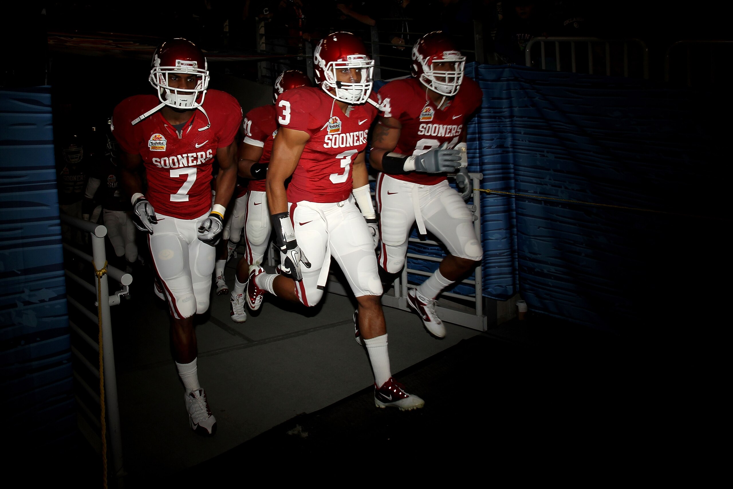 GLENDALE, AZ - JANUARY 01:  DeMarco Murray #7, Joe Powell #3 and Frank Alexander #84 of the Oklahoma Sooners run out onto the field before taking on Connecticut Huskies in the Tostitos Fiesta Bowl at the Universtity of Phoenix Stadium on January 1, 2011 i