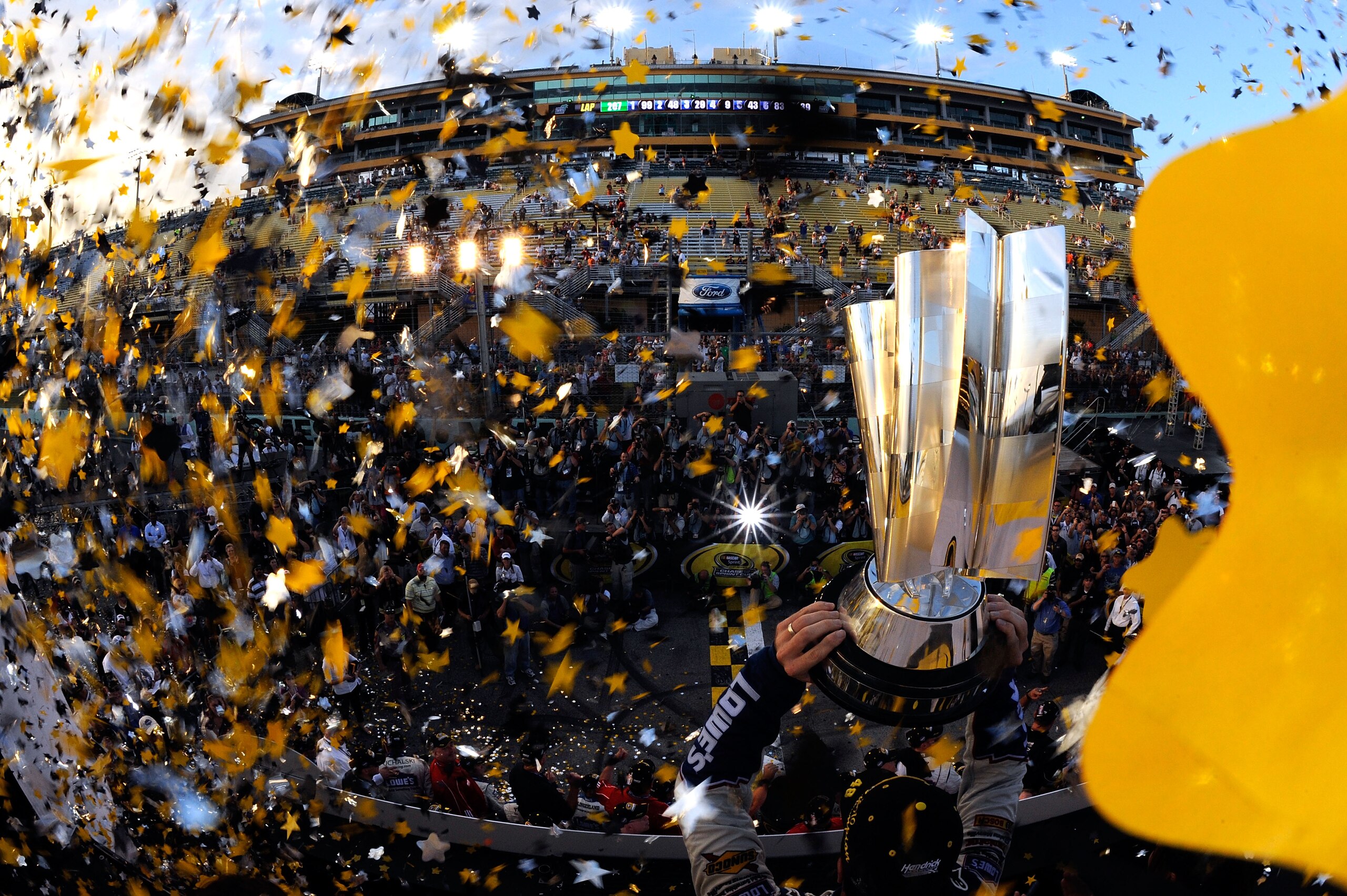 HOMESTEAD, FL - NOVEMBER 21:  Jimmie Johnson, driver of the #48 Lowe's Chevrolet, celebrates by hoisting the trophy after finishing in second place in the Ford 400 to clinch his fifth consecutive NASCAR Sprint Cup championship at Homestead-Miami Speedway