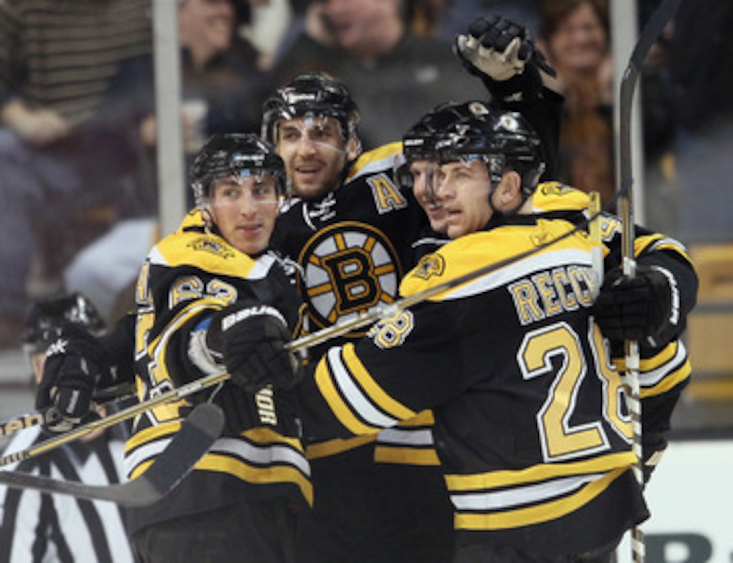 BOSTON, MA - JANUARY 13:  Patrice Bergeron #37 of the Boston Bruins is congratulated by teammates Brad Marchand #63,Mark Recchi #28 and Steven Kampfer #47 after Bergeron scored in the second period against the Philadelphia Flyers on January 13, 2011 at th