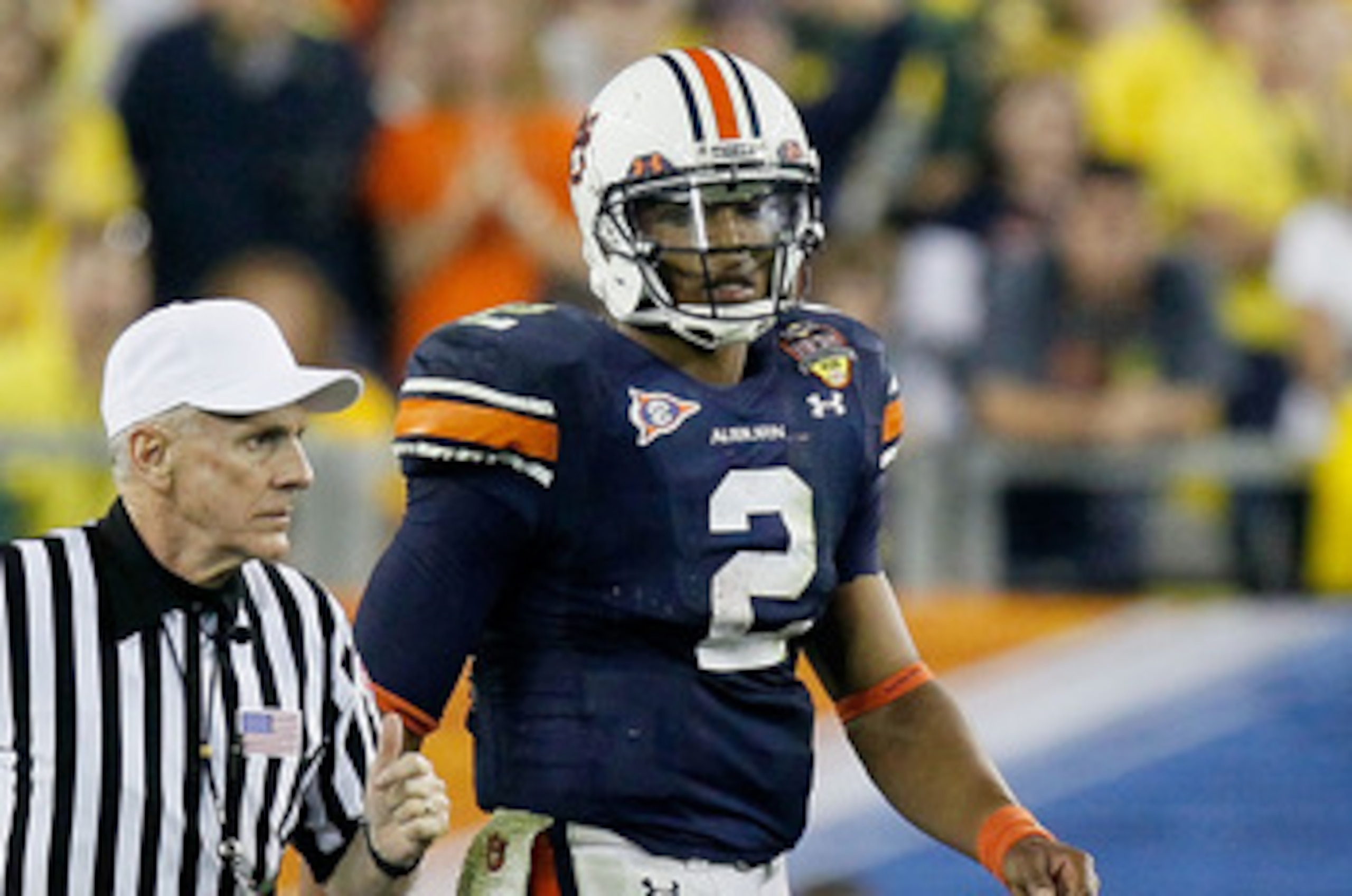 GLENDALE, AZ - JANUARY 10:  Cameron Newton #2 of the Auburn Tigers looks on as an official runs past during their game against the Oregon Ducks during the Tostitos BCS National Championship Game at University of Phoenix Stadium on January 10, 2011 in Glen