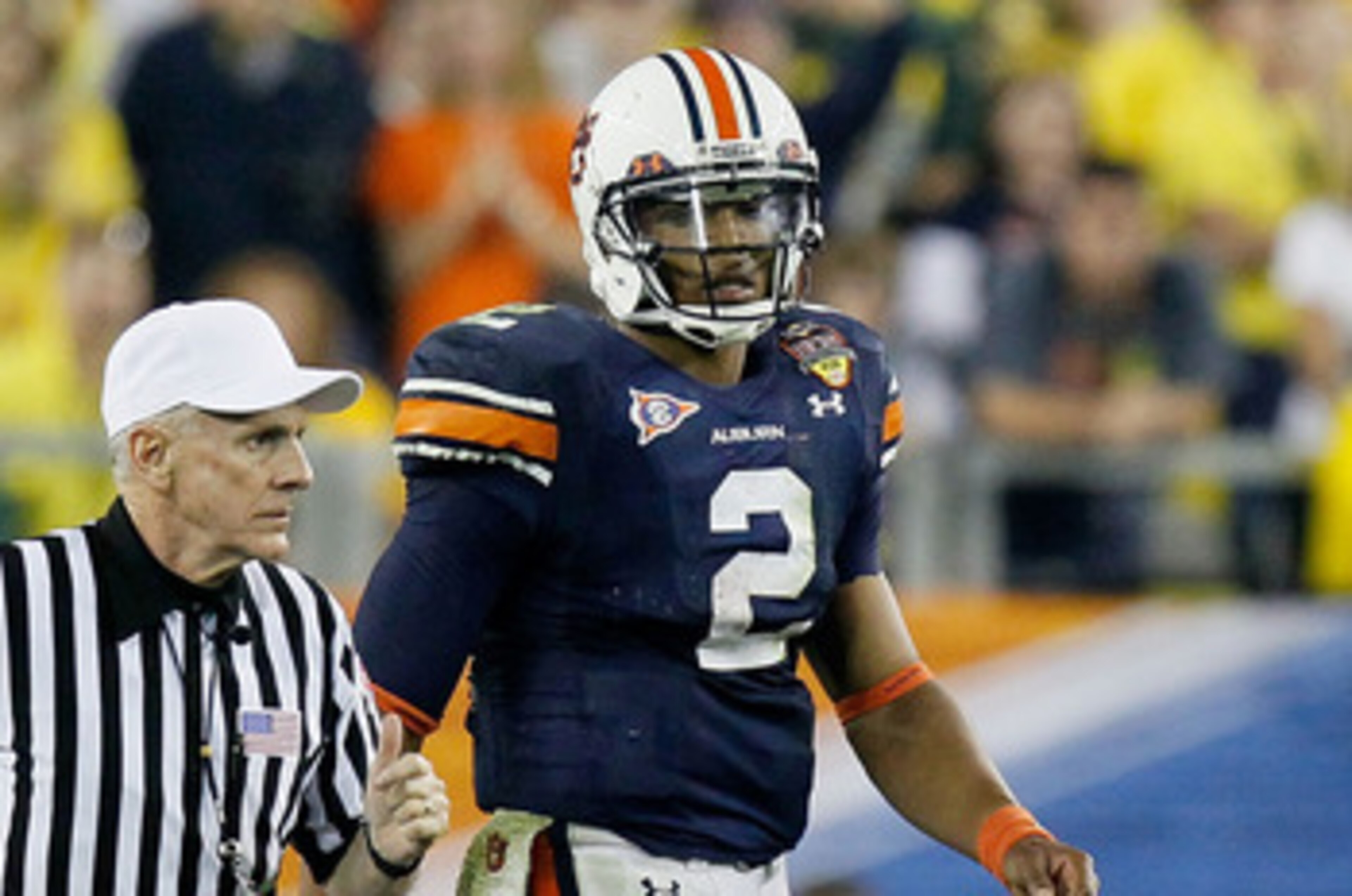 GLENDALE, AZ - JANUARY 10:  Cameron Newton #2 of the Auburn Tigers looks on as an official runs past during their game against the Oregon Ducks during the Tostitos BCS National Championship Game at University of Phoenix Stadium on January 10, 2011 in Glen