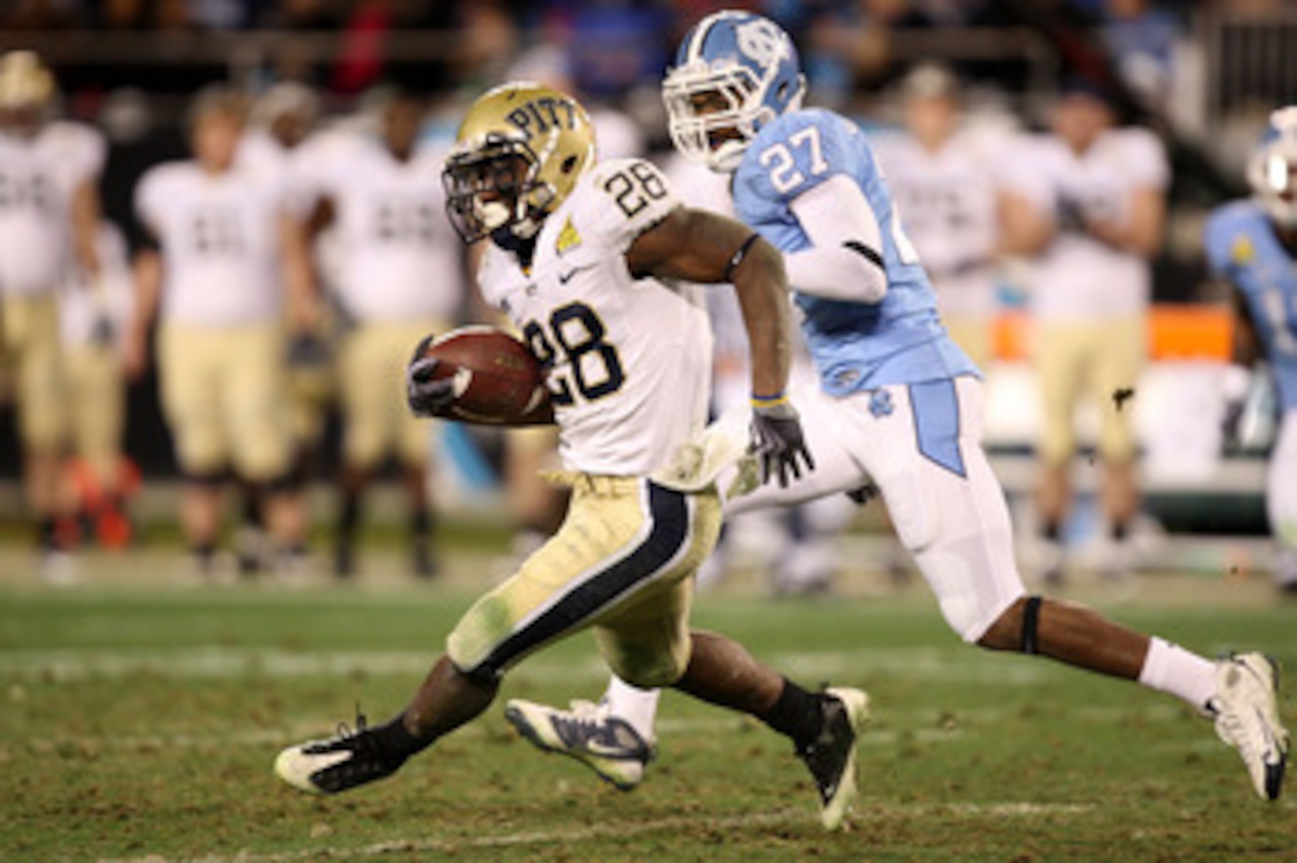 CHARLOTTE, NC - DECEMBER 26:  Dion Lewis #28 of the Pittsburgh Panthers runs away from Deunta Williams #27 of the North Carolina Tar Heels during their game on December 26, 2009 in Charlotte, North Carolina.  (Photo by Streeter Lecka/Getty Images)