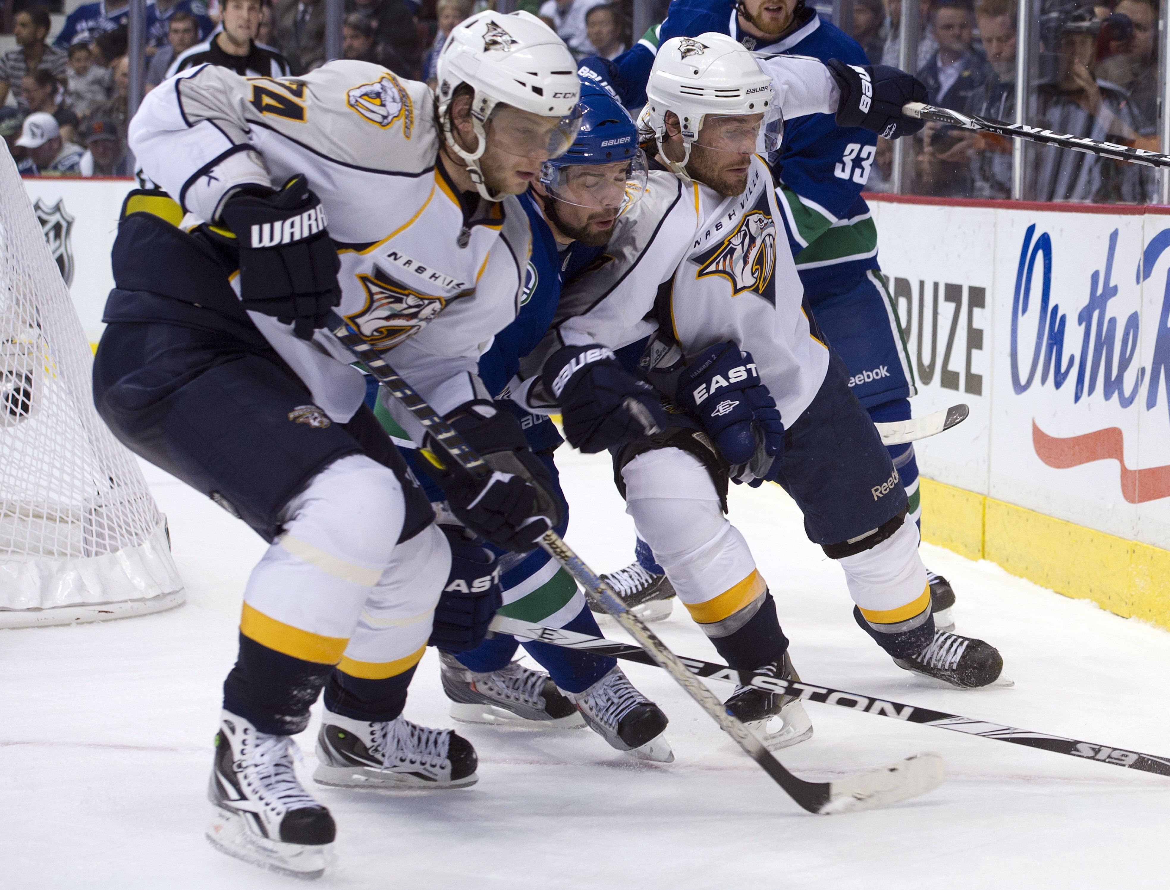 VANCOUVER, CANADA - APRIL 28: Dan Hamhuis #2 of the Vancouver Canucks is squeezed out by Sergei Kostitsyn #74 and Mike Fisher #12 of the Nashville Predators while chasing a loose puck in the corner during the third period in Game One of the Western Confer