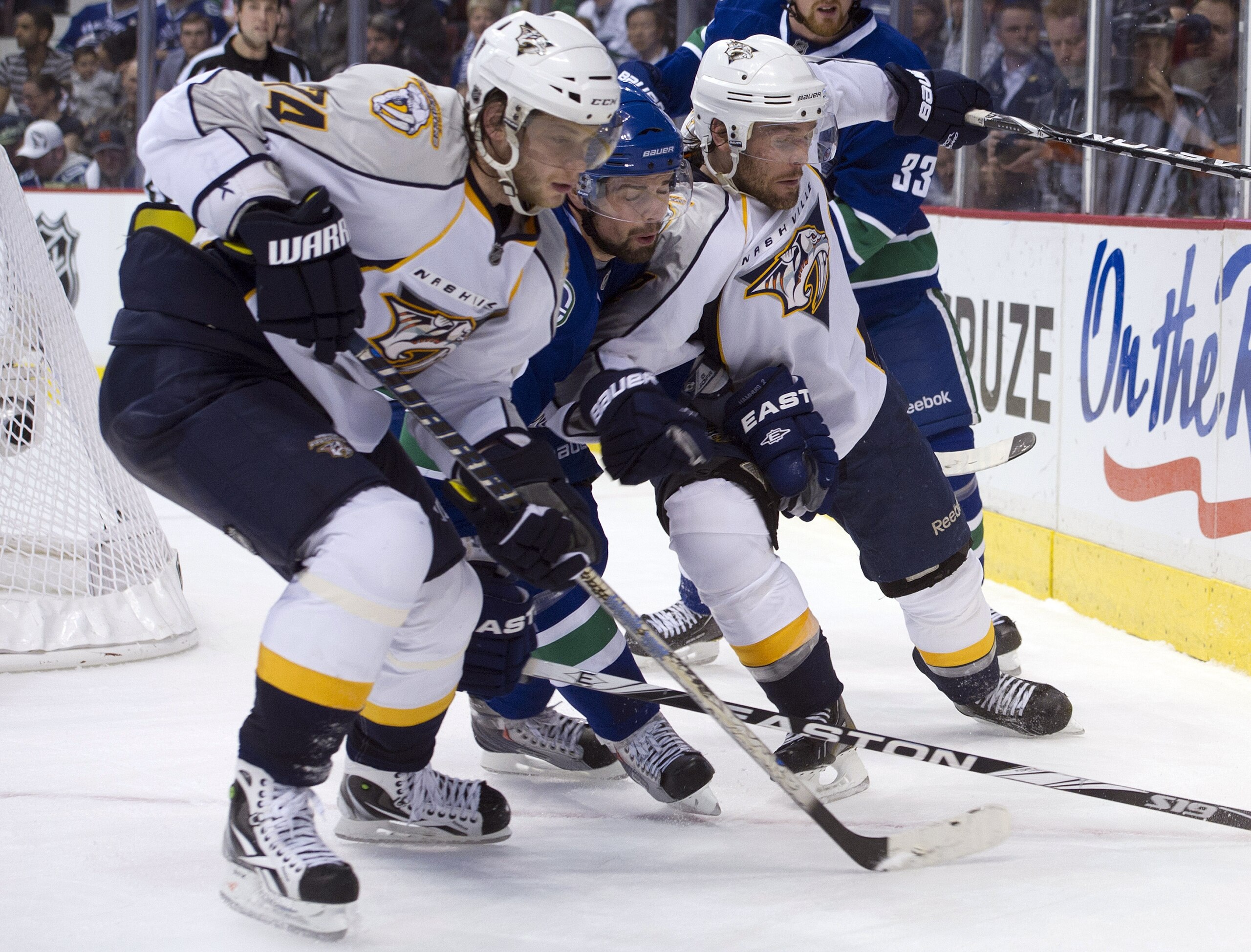 VANCOUVER, CANADA - APRIL 28: Dan Hamhuis #2 of the Vancouver Canucks is squeezed out by Sergei Kostitsyn #74 and Mike Fisher #12 of the Nashville Predators while chasing a loose puck in the corner during the third period in Game One of the Western Confer