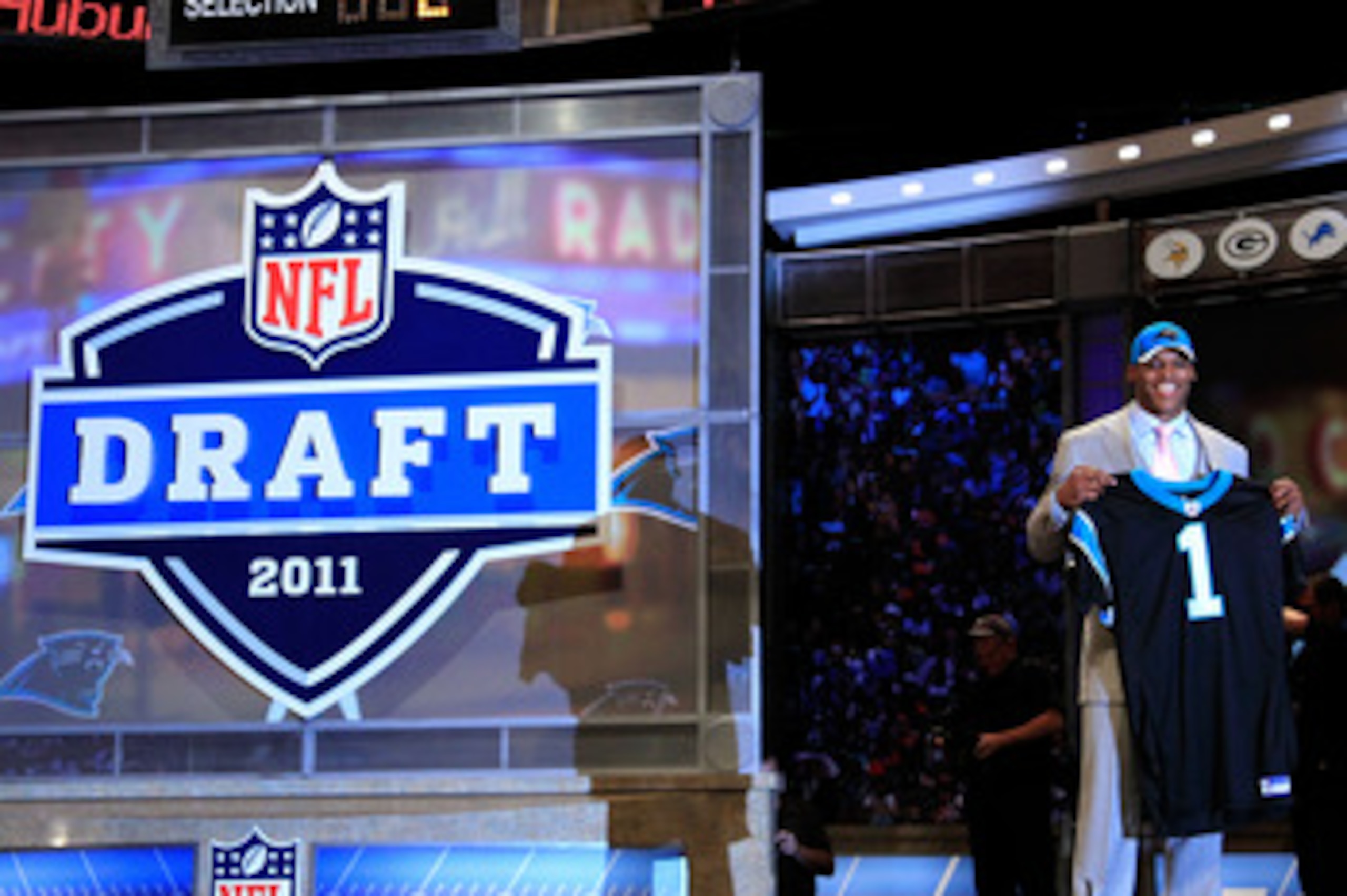 NEW YORK, NY - APRIL 28:  Cam Newton, #1 overall pick by the Carolina Panthers holds up a jersey on stage after he was picked during the 2011 NFL Draft at Radio City Music Hall on April 28, 2011 in New York City.  (Photo by Chris Trotman/Getty Images)