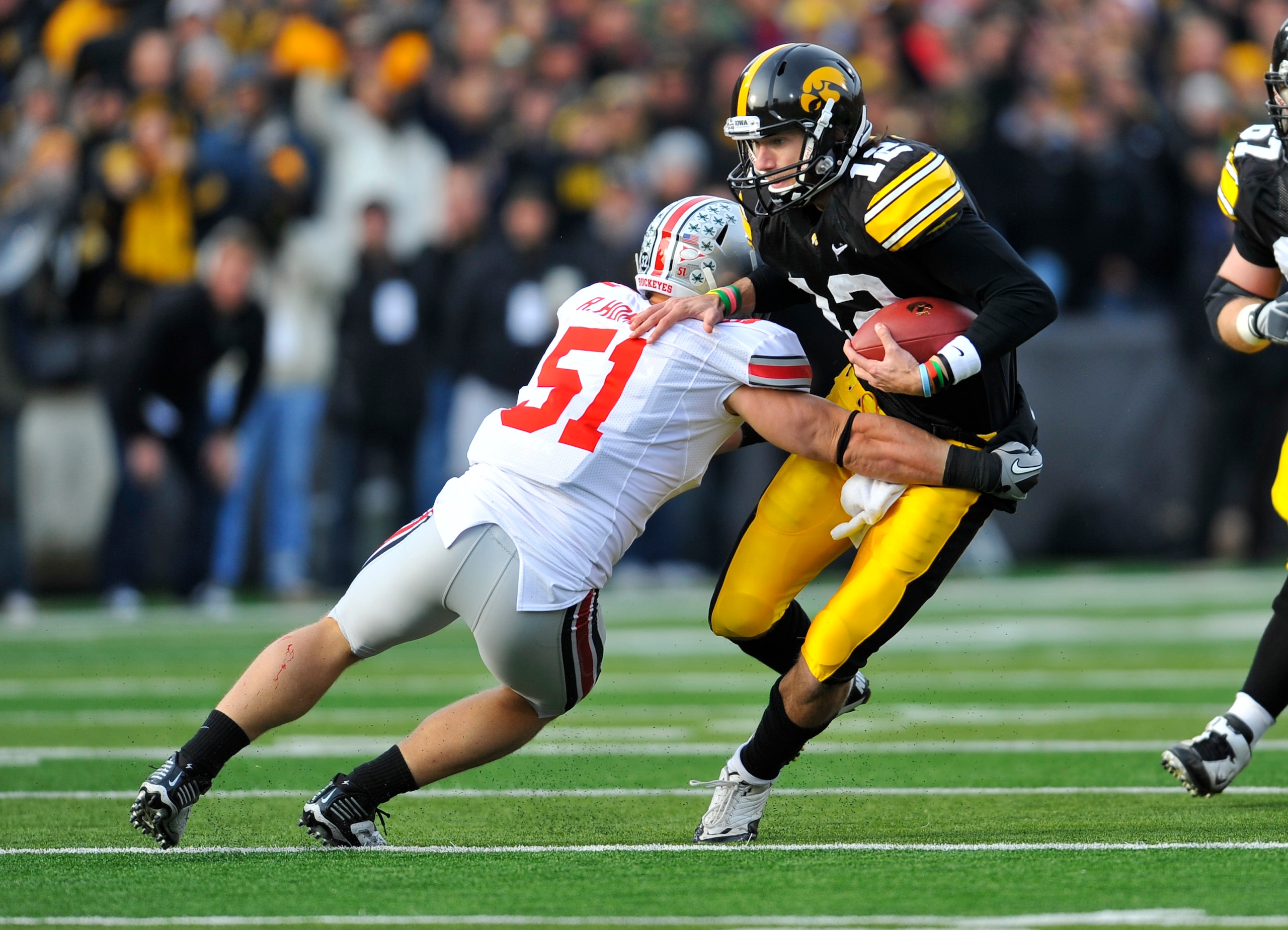IOWA CITY, IA - NOVEMBER 20:  Quarterback Ricky Stanzi #12 of the University of Iowa Hawkeyes scrambles for yards as linebacker Ross Homan #51 of the Ohio State Buckeyes defends during the first half of play at Kinnick Stadium on November 20, 2010 in Iowa