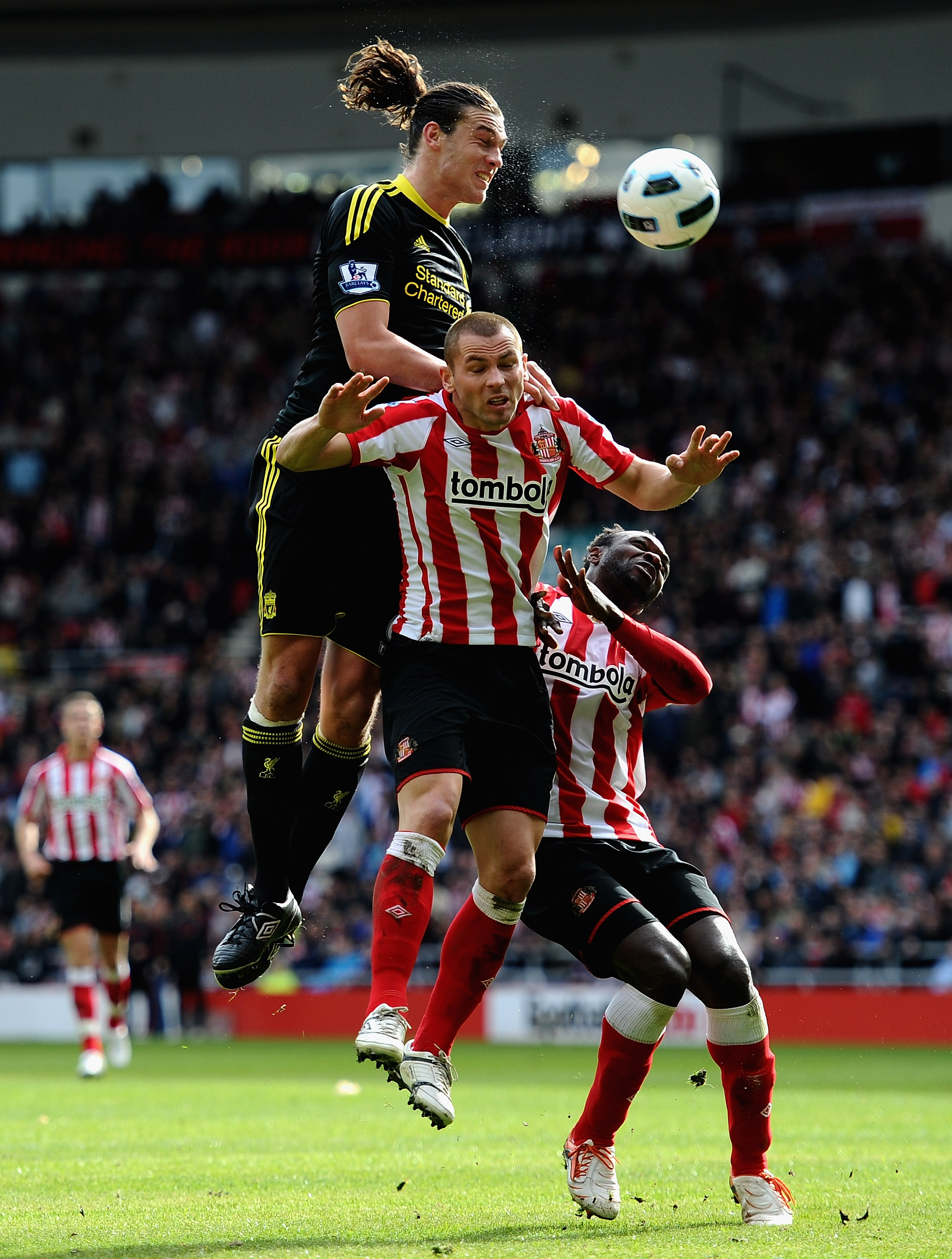 SUNDERLAND, ENGLAND - MARCH 20: Andy Carroll of Liverpool battles with Phil Bardsley and John Mensah of Sunderland during the Barclays Premier League match between Sunderland and Liverpool at the Stadium of Light on March 20, 2011 in Sunderland, England.