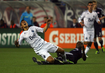 FOXBORO, MA - MAY 14:  Long Tan #23 of the Vancouver Whitecaps FC trips over Shalrie Joseph #21 of the New England Revolution at Gillette Stadium May 14, 2011 in Foxboro, Massachusetts. (Photo by Gail Oskin/Getty Images)