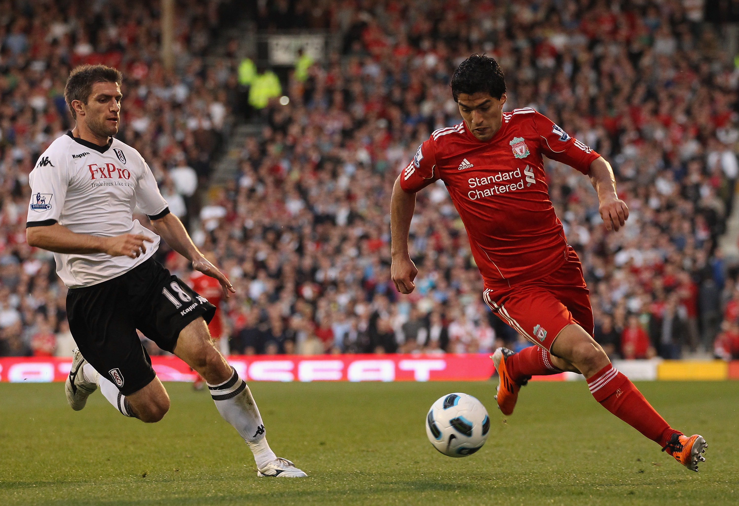 LONDON, ENGLAND - MAY 09:  Luis Suarez of Liverpool is challenged by Aaron Hughes of Fulham during the Barclays Premier League match between Fulham and Liverpool at Craven Cottage on May 9, 2011 in London, England.  (Photo by Scott Heavey/Getty Images)