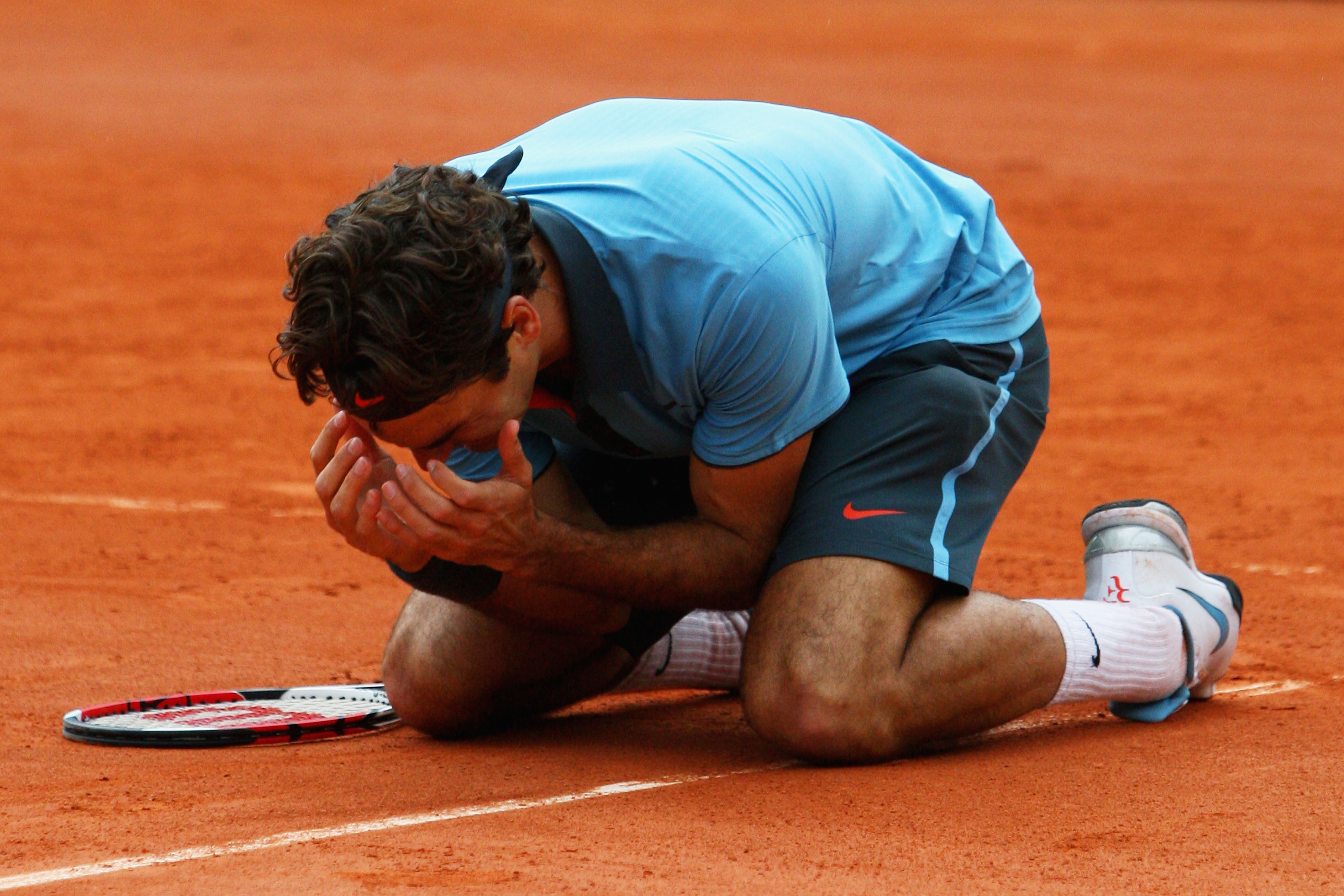 PARIS - JUNE 07:  Roger Federer of Switzerland falls to his knees as he celebrates victory during the Men's Singles Final match against Robin Soderling of Sweden on day fifteen of the French Open at Roland Garros on June 7, 2009 in Paris, France.  (Photo