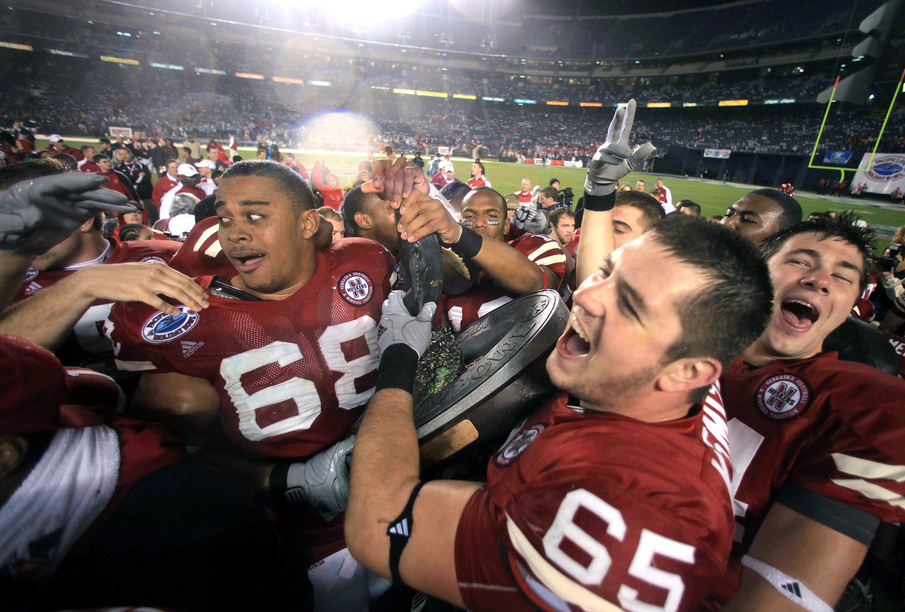 SAN DIEGO, CA - DECEMBER 30: Keith Williams #68, Mike Smith #65, and Mike McNeill #44 of the University of Nebraska Cornhuskers hoist the bowl trophy after defeating the University of Arizona Wildcats during the Pacific Life Holiday Bowl, on December 30,