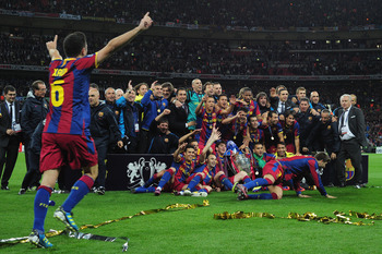 LONDON, ENGLAND - MAY 28:  Xavi (L) runs to join teammates ad Barcelona pose for photographs as they celebrate victory in the UEFA Champions League final between FC Barcelona and Manchester United FC at Wembley Stadium on May 28, 2011 in London, England.