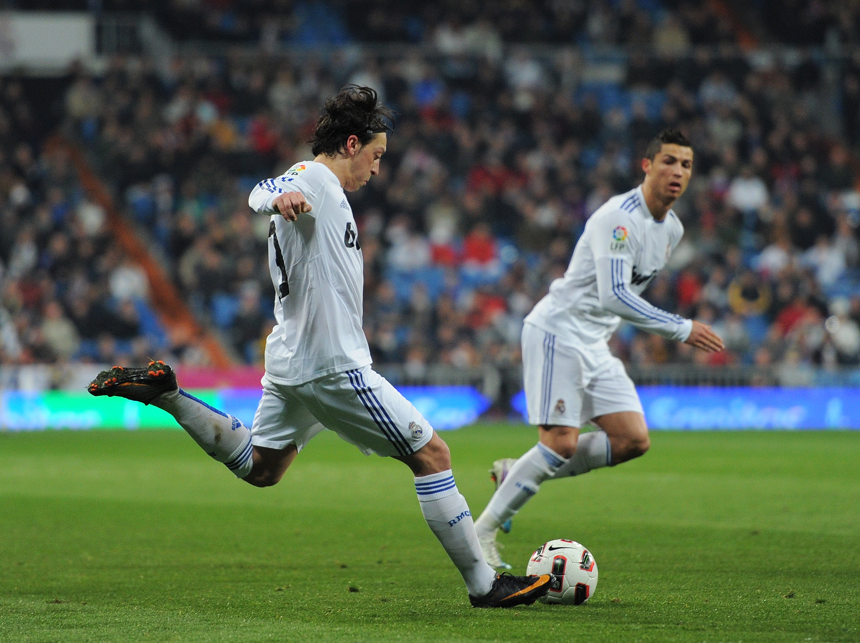 MADRID, SPAIN - MARCH 03:  Mesut Ozil of Real Madrid strikes a free kick to hit the goal post backdropped by his teammate Cristiano Ronaldo during the la Liga match between Real Madrid and Malaga at Estadio Santiago Bernabeu on March 3, 2011 in Madrid, Sp