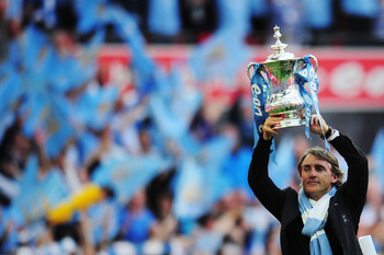 LONDON, ENGLAND - MAY 14:  Roberto Mancini lifts the trophy after his Manchester City team wins the FA Cup sponsored by E.ON Final match between Manchester City and Stoke City at Wembley Stadium on May 14, 2011 in London, England.  (Photo by Shaun Botteri