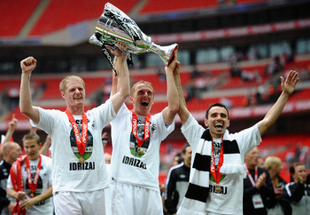 LONDON, ENGLAND - MAY 30: Garry Monk of Swansea (c) lifts the trophy as they celebrate promotion to the Premier League with Alan Tate (l) and Leon Britton during the npower Championship Playoff Final between Reading and Swansea City at Wembley Stadium on 