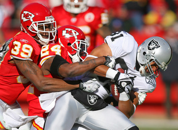 KANSAS CITY, MO - JANUARY 02:  Wide receiver Chaz Schilens #81 of the Oakland Raiders is tackled by Brandon Carr #39 and Brandon Flowers #24 of the Kansas City Chiefs in a game at Arrowhead Stadium on January 2, 2011 in Kansas City, Missouri.  (Photo by T