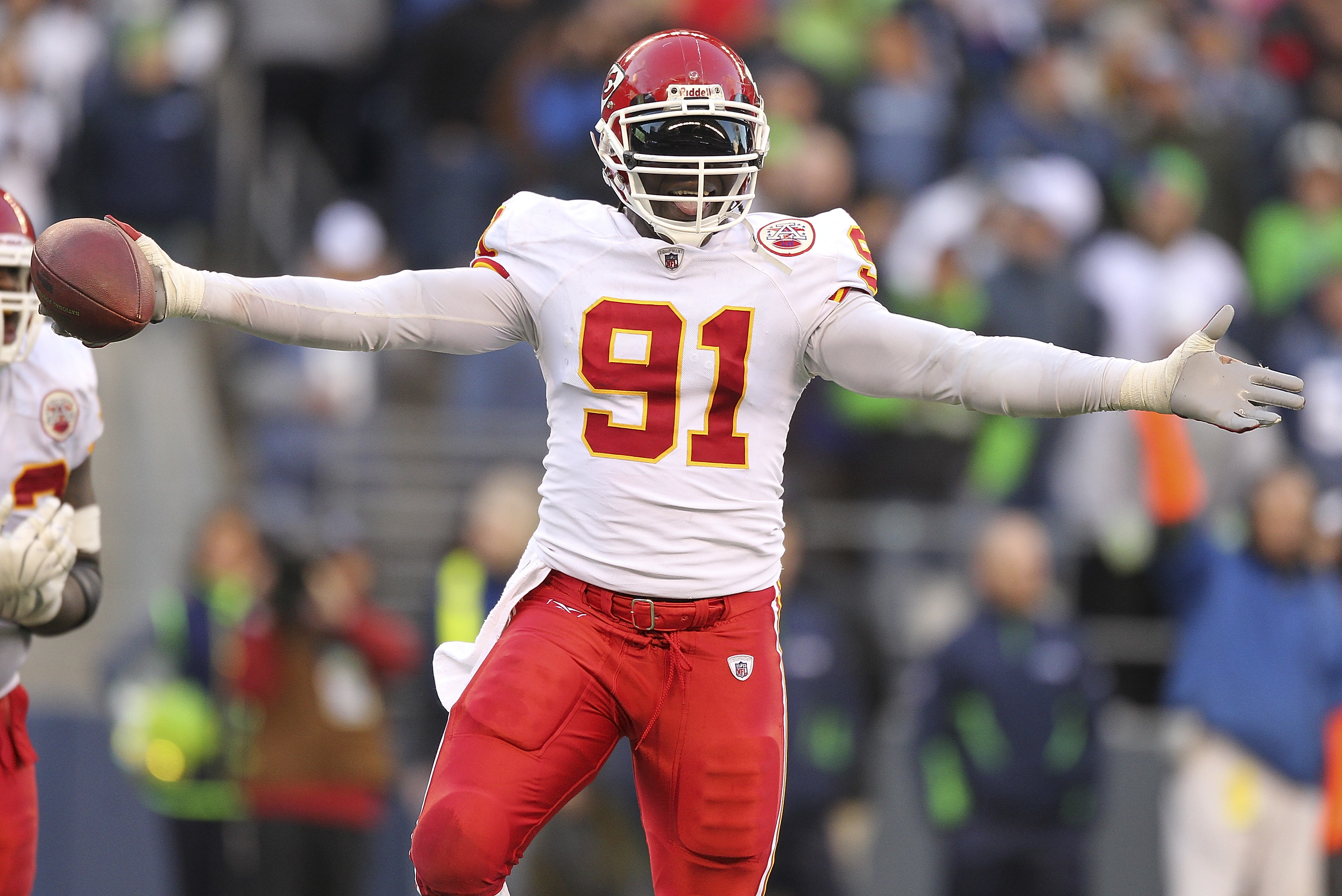 The Kansas City Chiefs - Tamba Hali gets a helping hand by a young Chiefs  fan carrying his helmet after practice.