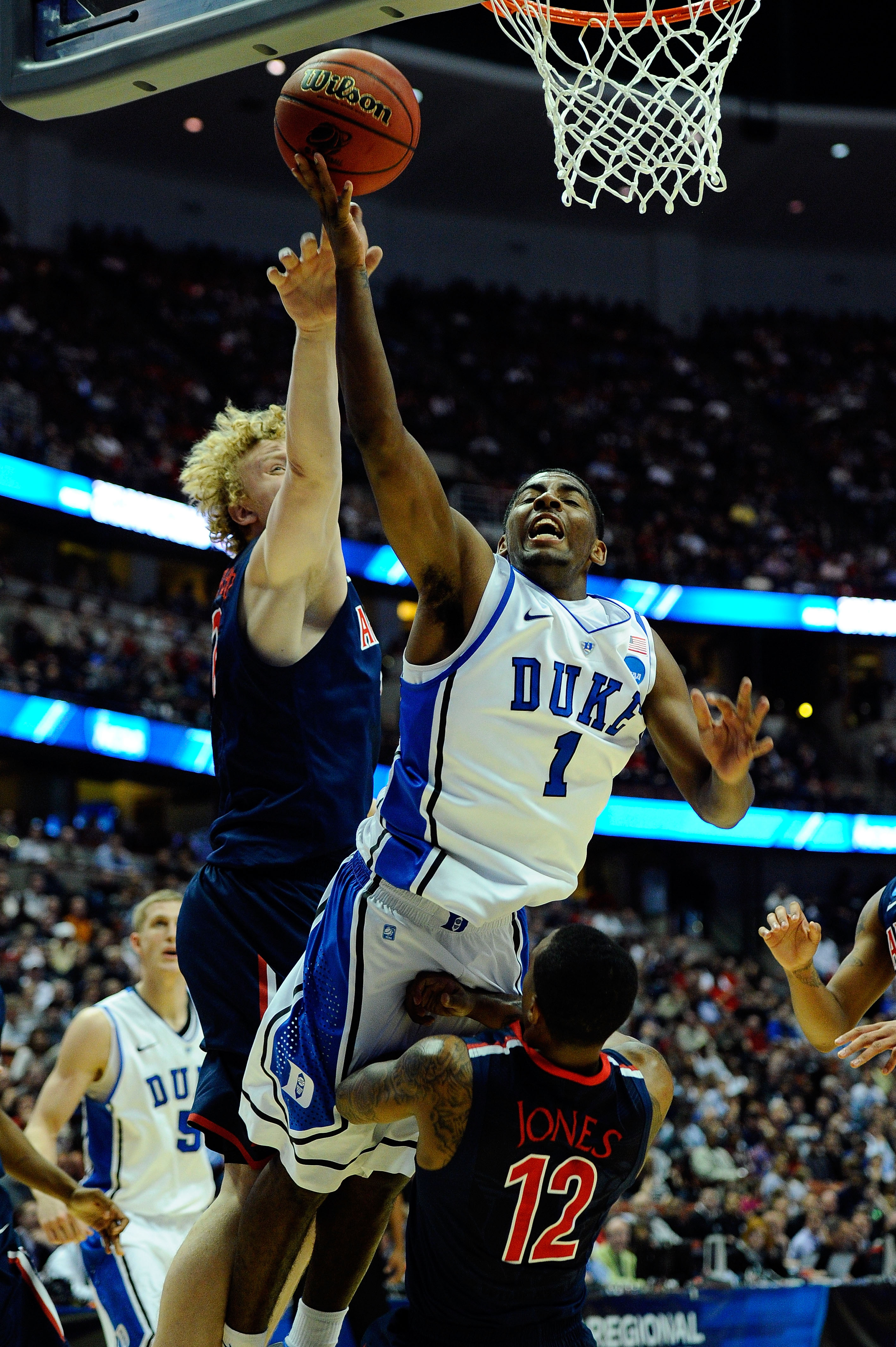 ANAHEIM, CA - MARCH 24:  Kyrie Irving #1 of the Duke Blue Devils draws contact against Kyryl Natyazhko #1 and Lamont Jones #12 of the Arizona Wildcats during the west regional semifinal of the 2011 NCAA men's basketball tournament at the Honda Center on M