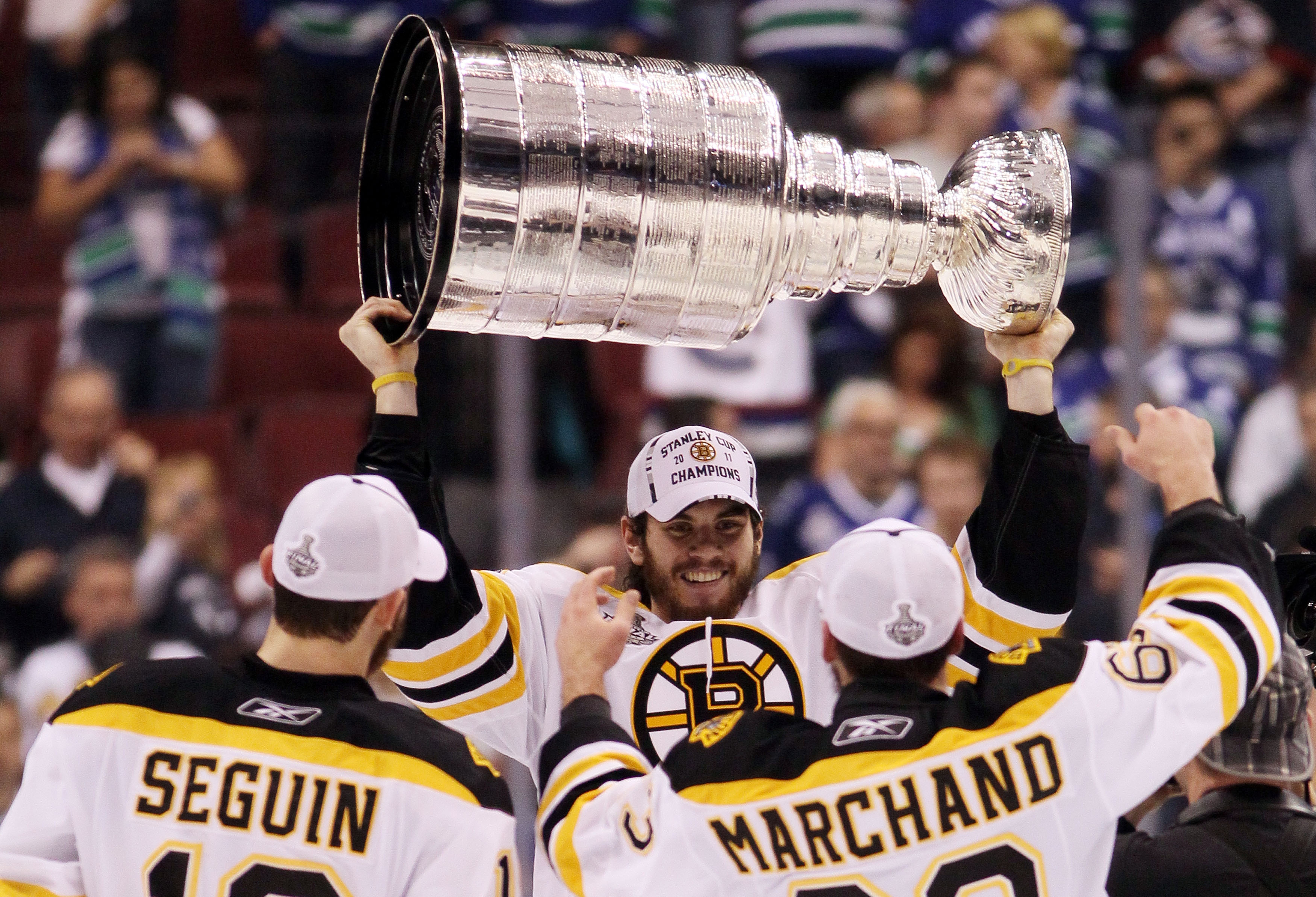 VANCOUVER, BC - JUNE 15:  Adam McQuaid #54 of the Boston Bruins hands the Stanley Cup to Brad Marchand #63 after defeating the Vancouver Canucks in Game Seven of the 2011 NHL Stanley Cup Final at Rogers Arena on June 15, 2011 in Vancouver, British Columbi