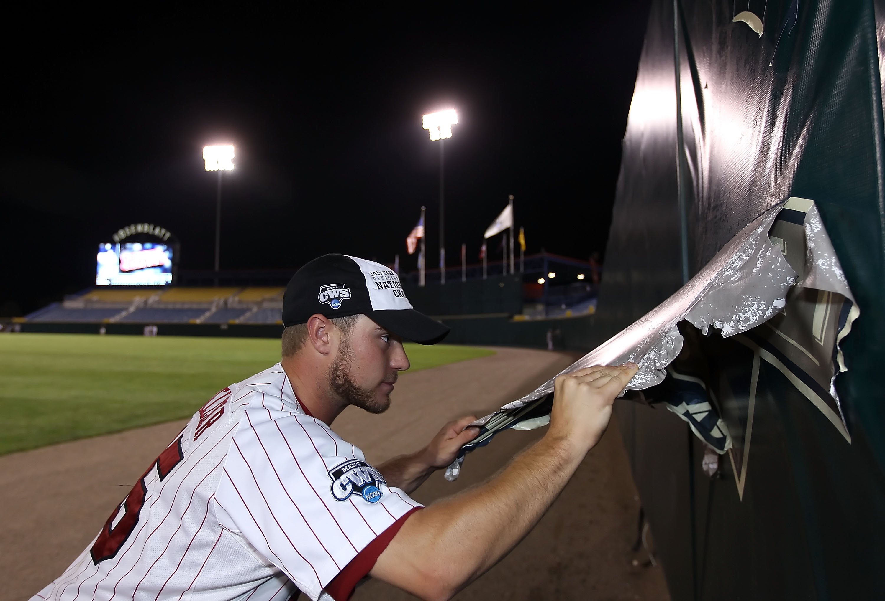 OMAHA, NE - JUNE 29: Nolan Belcher #15 of the South Carolina Gamecocks tears down a logo from the outfield wall after defeating the UCLA Bruins in game 2 of the men's 2010 NCAA College Baseball World Series at Rosenblatt Stadium on June 29, 2010 in Omaha