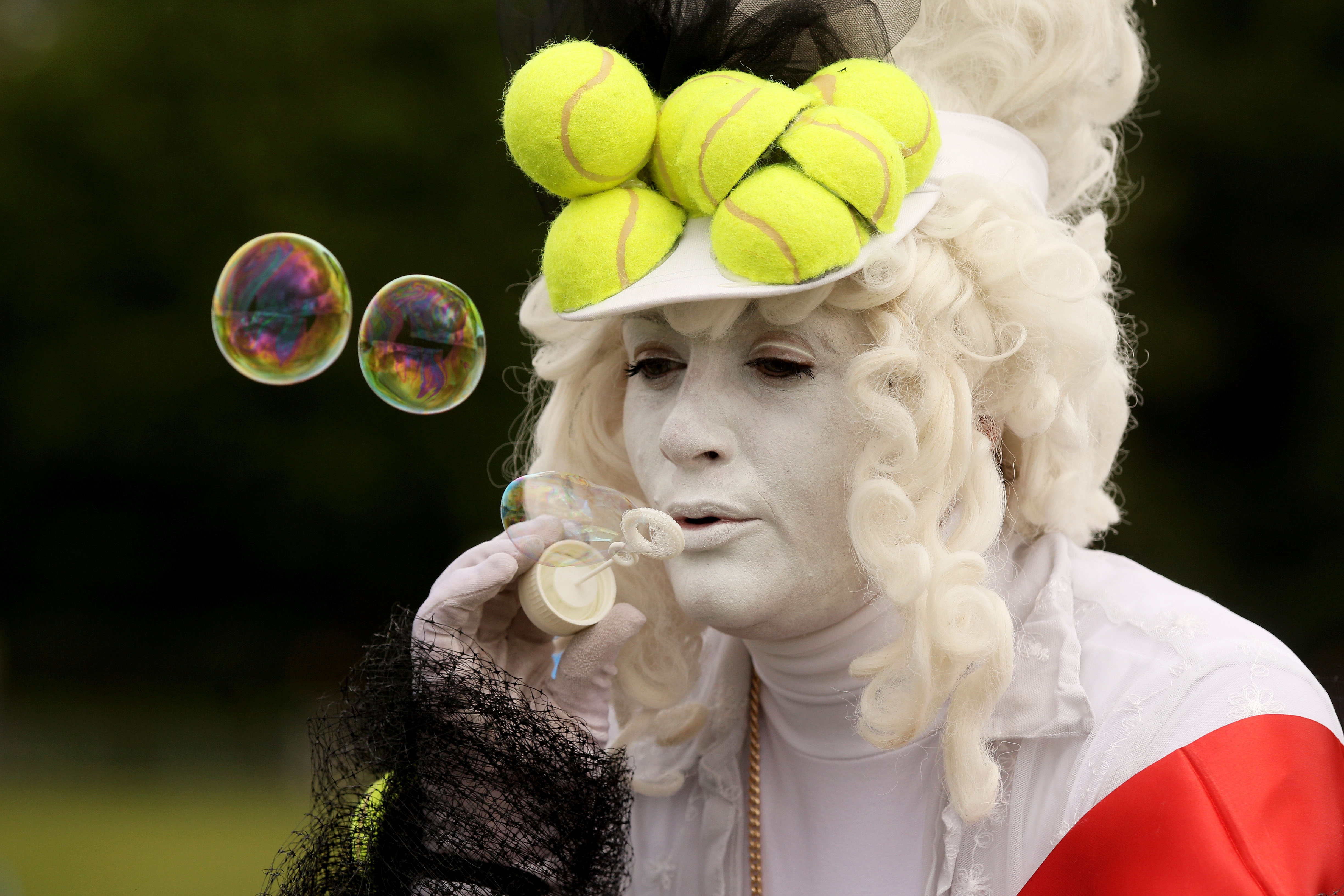 LONDON, ENGLAND - JUNE 21:  A tennis fan blows bubbles while waiting in a queue to enter the grounds on Day Two of the Wimbledon Lawn Tennis Championships at the All England Lawn Tennis and Croquet Club on June 21, 2011 in London, England.  (Photo by Oli