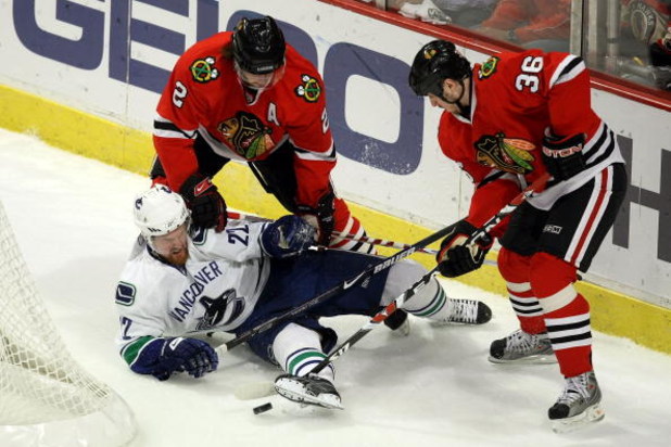 CHICAGO - MAY 05:  Daniel Sedin #22 of the Vancouver Canucks fights for the puck behind the net against Duncan Keith #2 and Dave Bolland #36 of the Chicago Blackhawks during the first period of Game Three of the Western Conference Semifinal Round of the 2