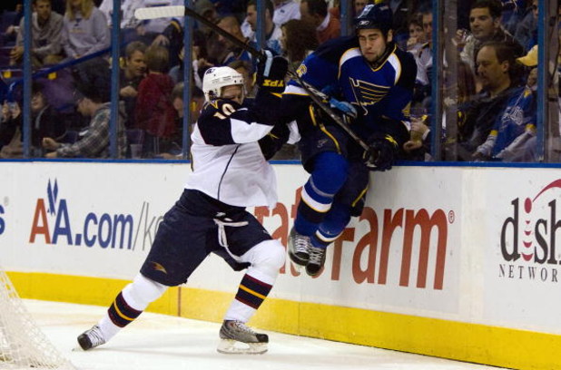 ST. LOUIS, MO - OCTOBER 8: Bryan Little #10 of the Atlanta Thrashers checks Roman Polak #26 of the St. Louis Blues into the boards at the Scottrade Center on October 8, 2009 in St. Louis, Missouri.  (Photo by Dilip Vishwanat/Getty Images)
