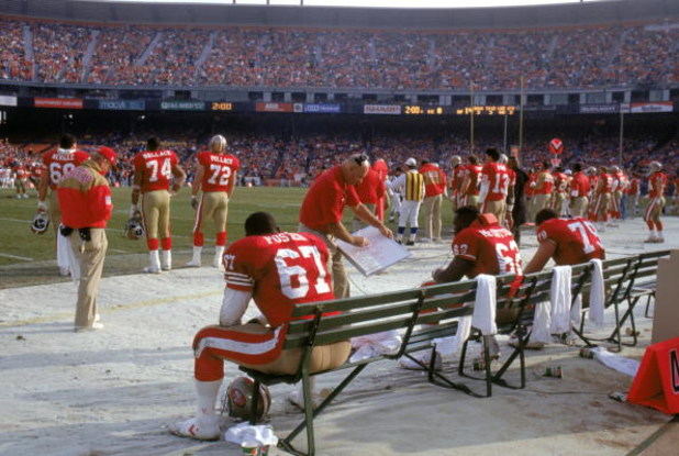 SAN FRANCISCO - DECEMBER 14:  Offensive line coach Bobb Mckittrick of the San Francisco 49ers talks with his offensive linemen Roy Foster #67, Guy McIntyre #62 and Harris Barton #79 during a game against the Kansas City Chiefs at Candlestick Park on Decem