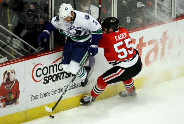 CHICAGO - MAY 05:  Kevin Bieksa #3 of the Vancouver Canucks avoids an attempted check by Ben Eager #55 of the Chicago Blackhawks during the first period of Game Three of the Western Conference Semifinal Round of the 2009 Stanley Cup Playoffs on May 5, 200