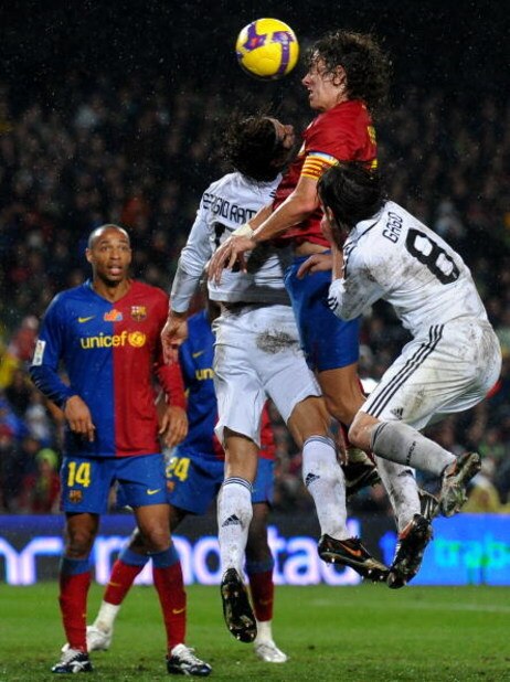 BARCELONA, SPAIN - DECEMBER 13: Carles Puyol (2nd R) of Barcelona goes for a high ball with Fernando Gago (R) and Sergio Ramos (2nd L) of Real Madrid as Barcelona player Thierry Henry looks on during the La Liga match between Barcelona and Real Madrid at
