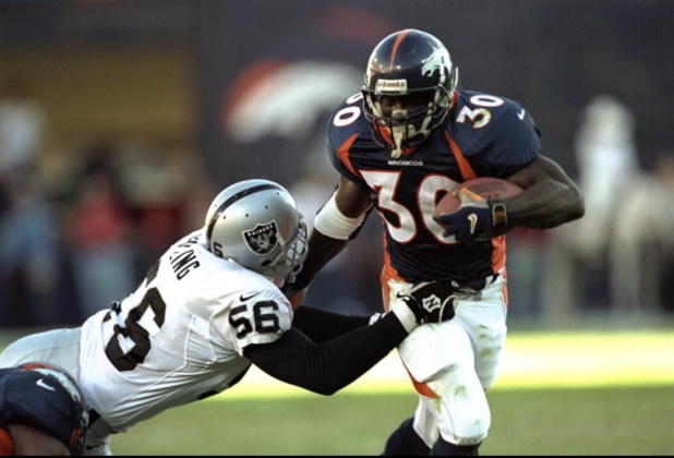22 Nov 1998:  Running back Terrell Davis #30 of the Denver Broncos in action against defensive end Pat Swilling #56 of the Oakland Raiders during the game at the Mile High Stadium in Denver, Colorado. The Broncos defeated the Raiders 40-14. Mandatory Cred